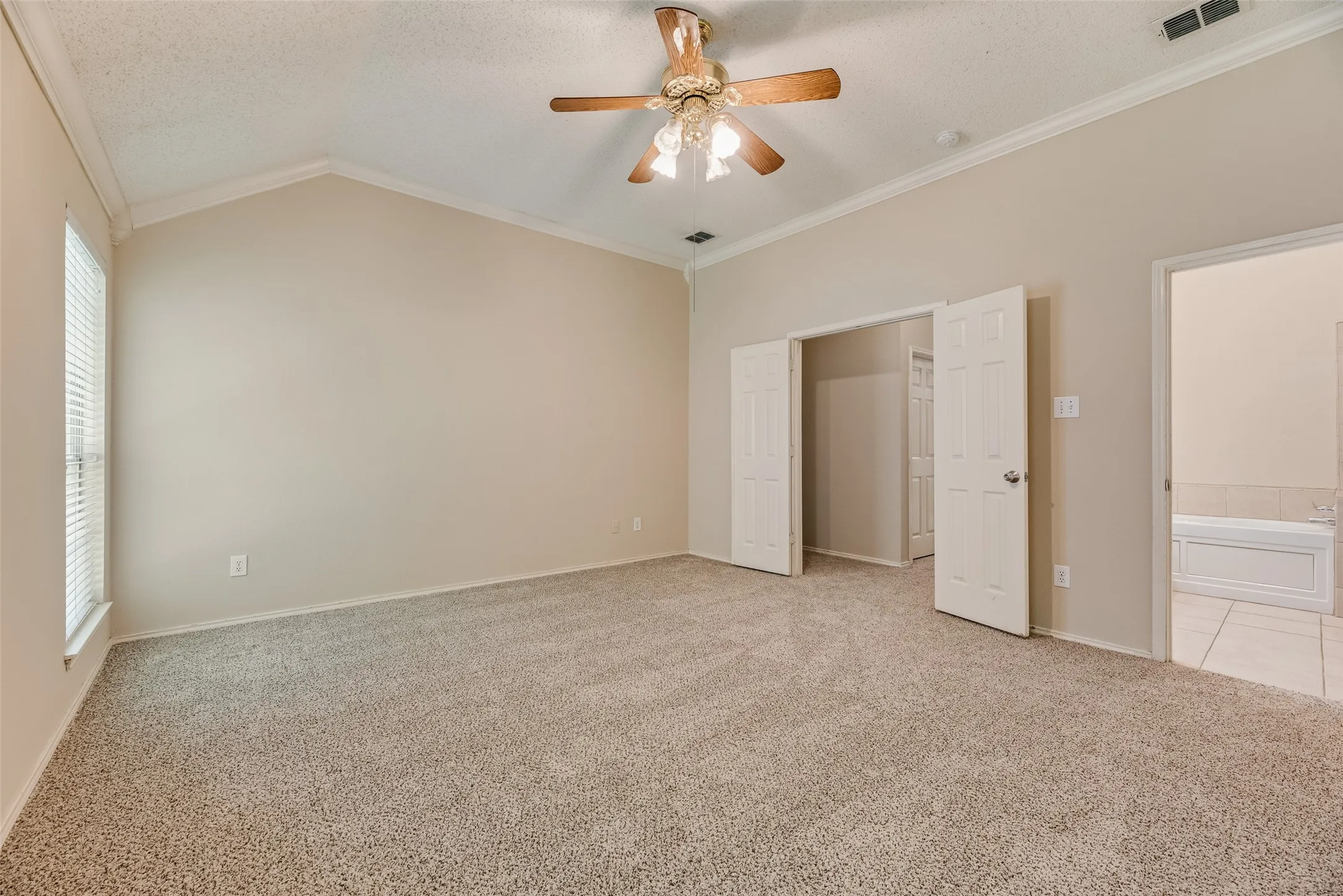 Vaulted ceiling bedroom with a ceiling fan light fixture and neutral-toned carpeting