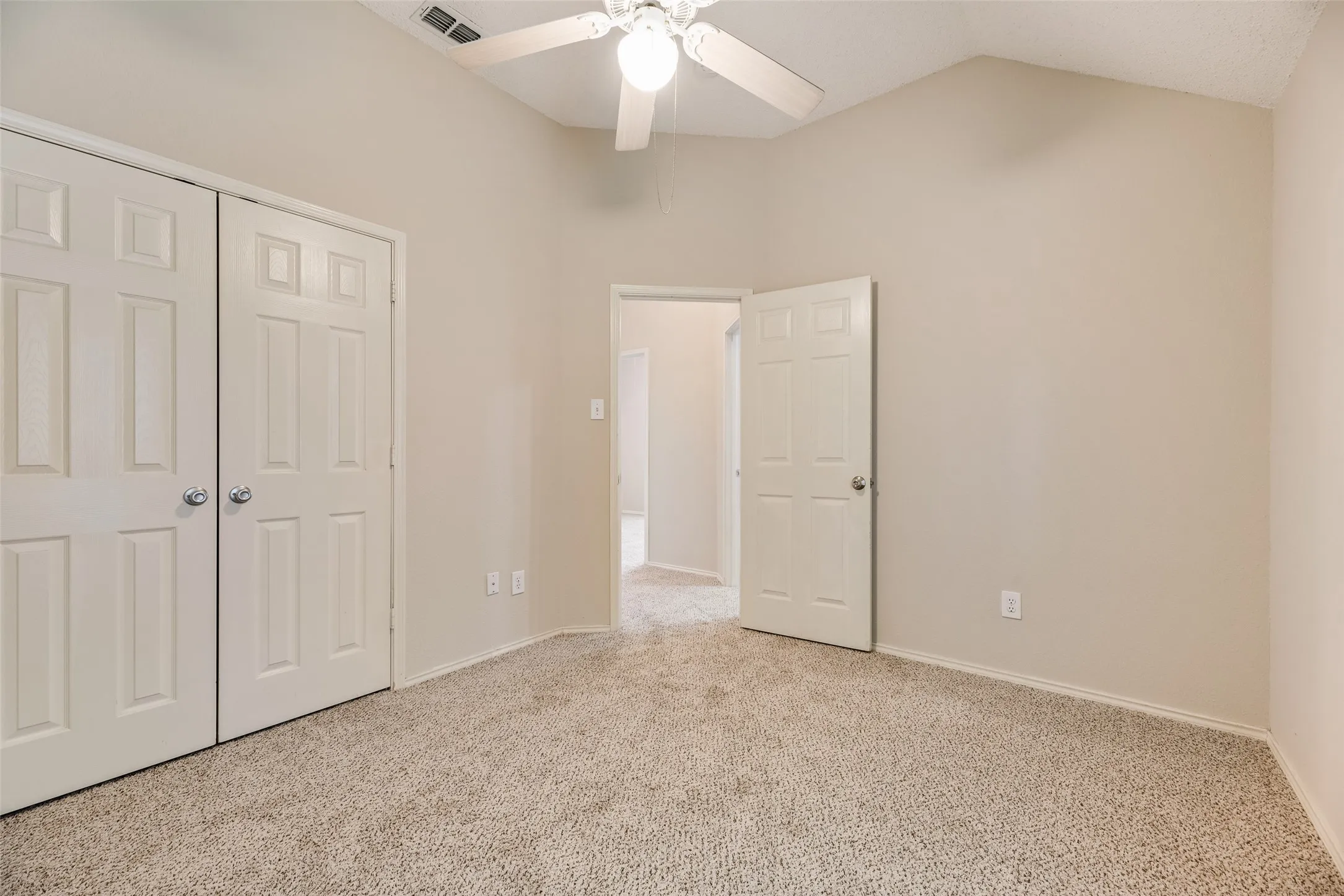 Carpeted room with vaulted ceilings and a ceiling fan