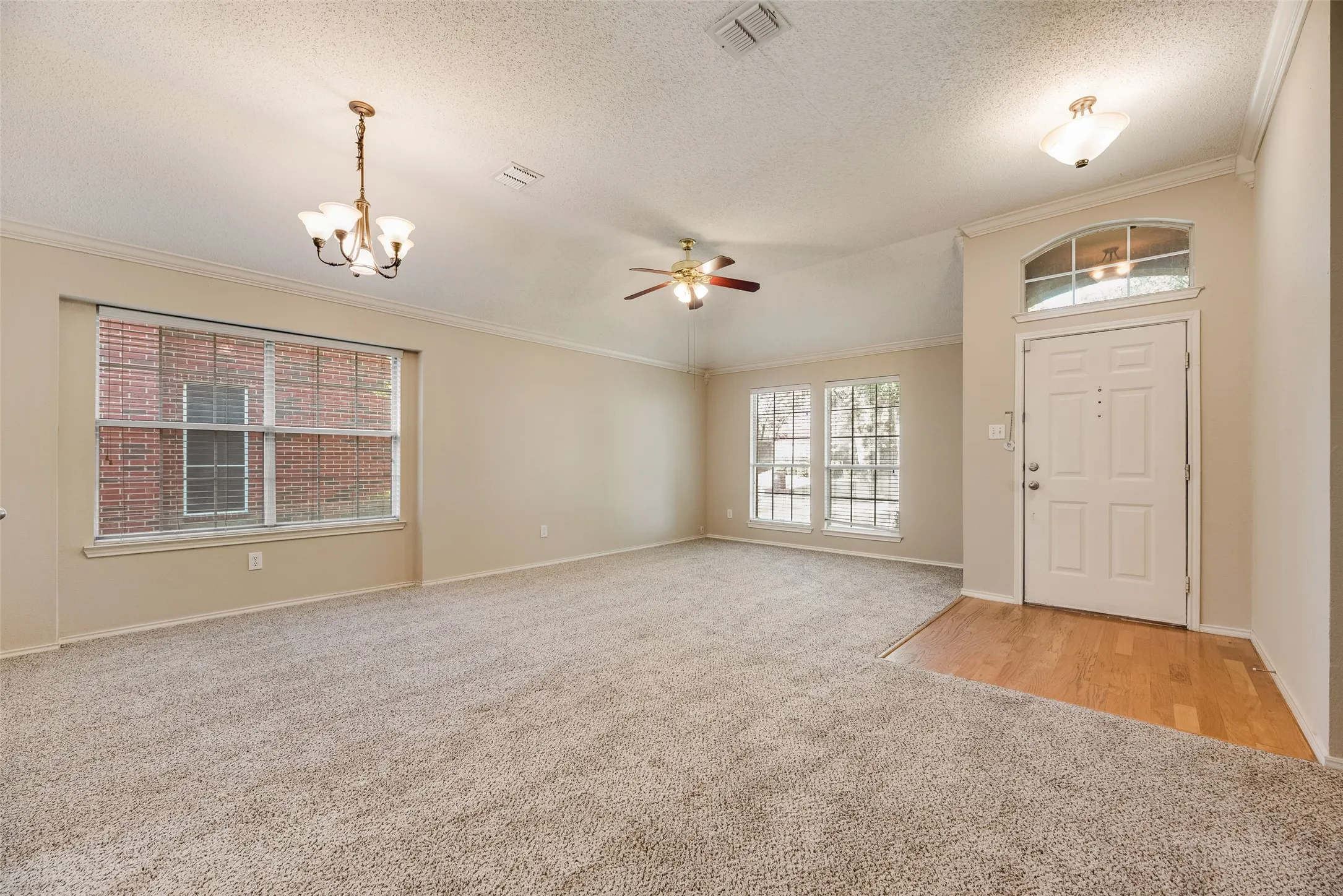 Spacious entry with wood-finish flooring opening to a carpeted living area