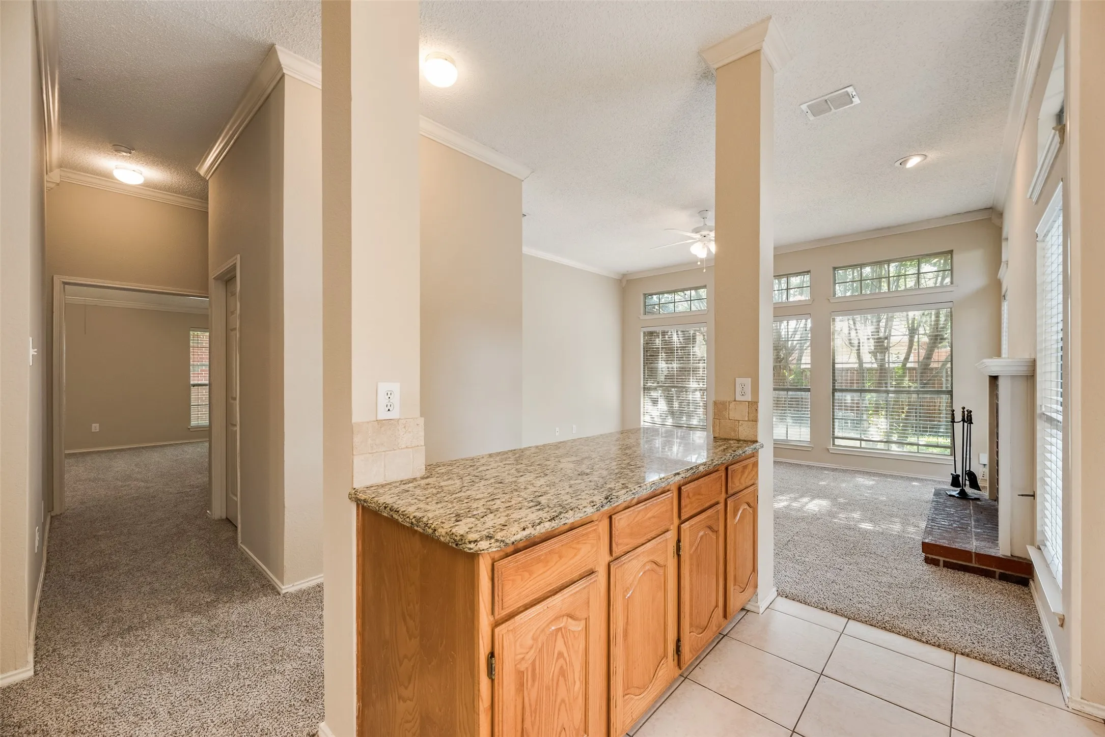 Kitchen counter bar featuring a granite-style countertop, wood cabinetry, and a tile backsplash