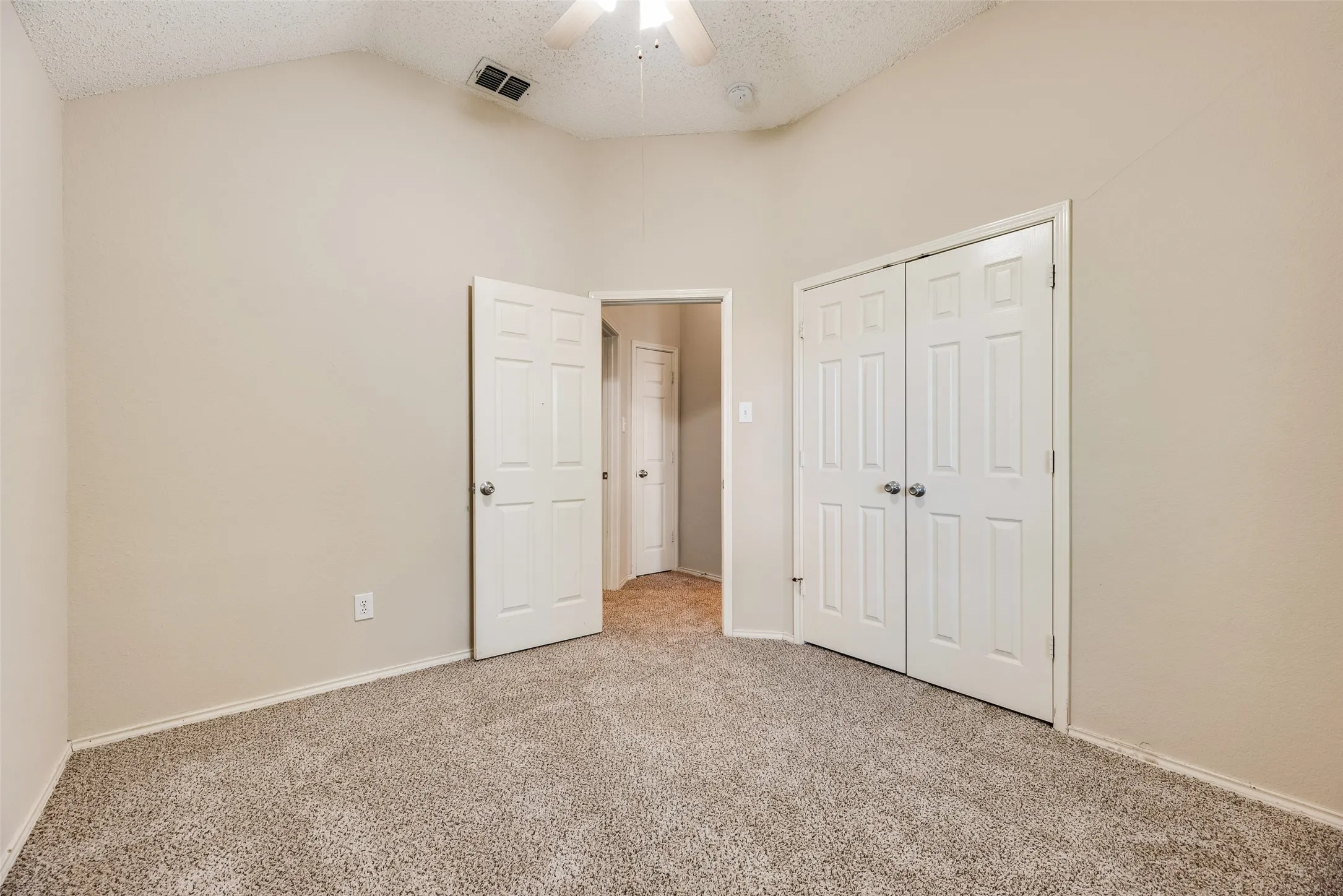 Room featuring vaulted ceilings, neutral wall paint, and textured carpeting