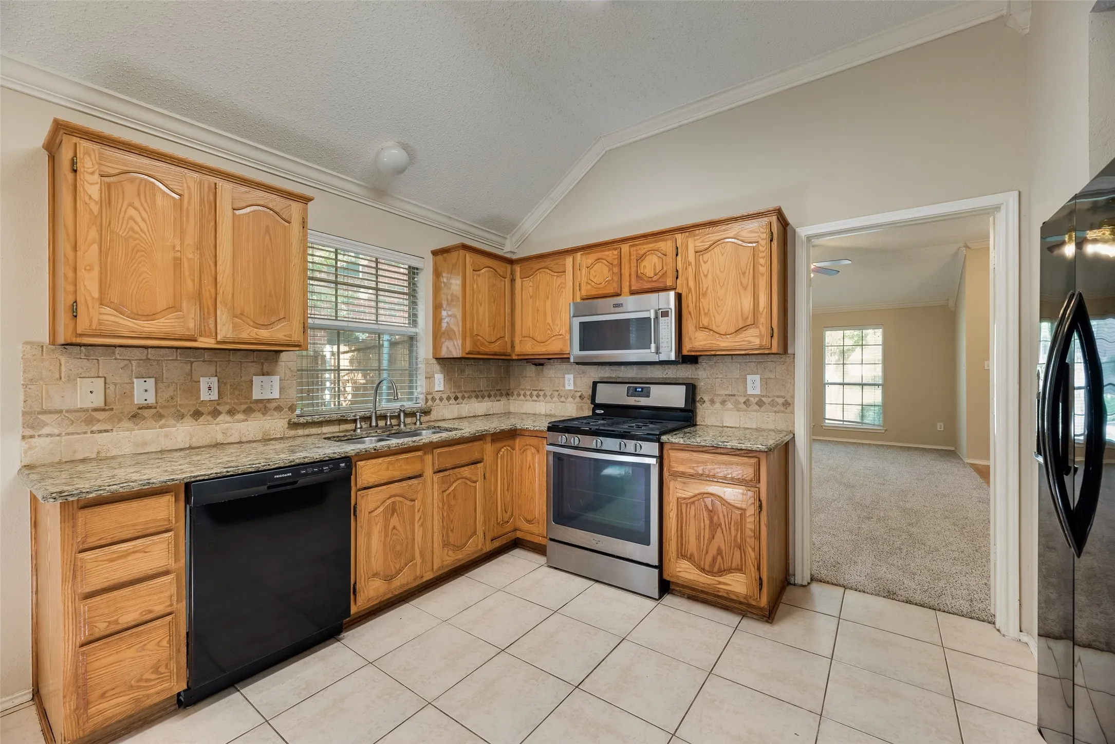 Kitchen featuring wood cabinetry, granite countertops, tile backsplash, and stainless steel appliances