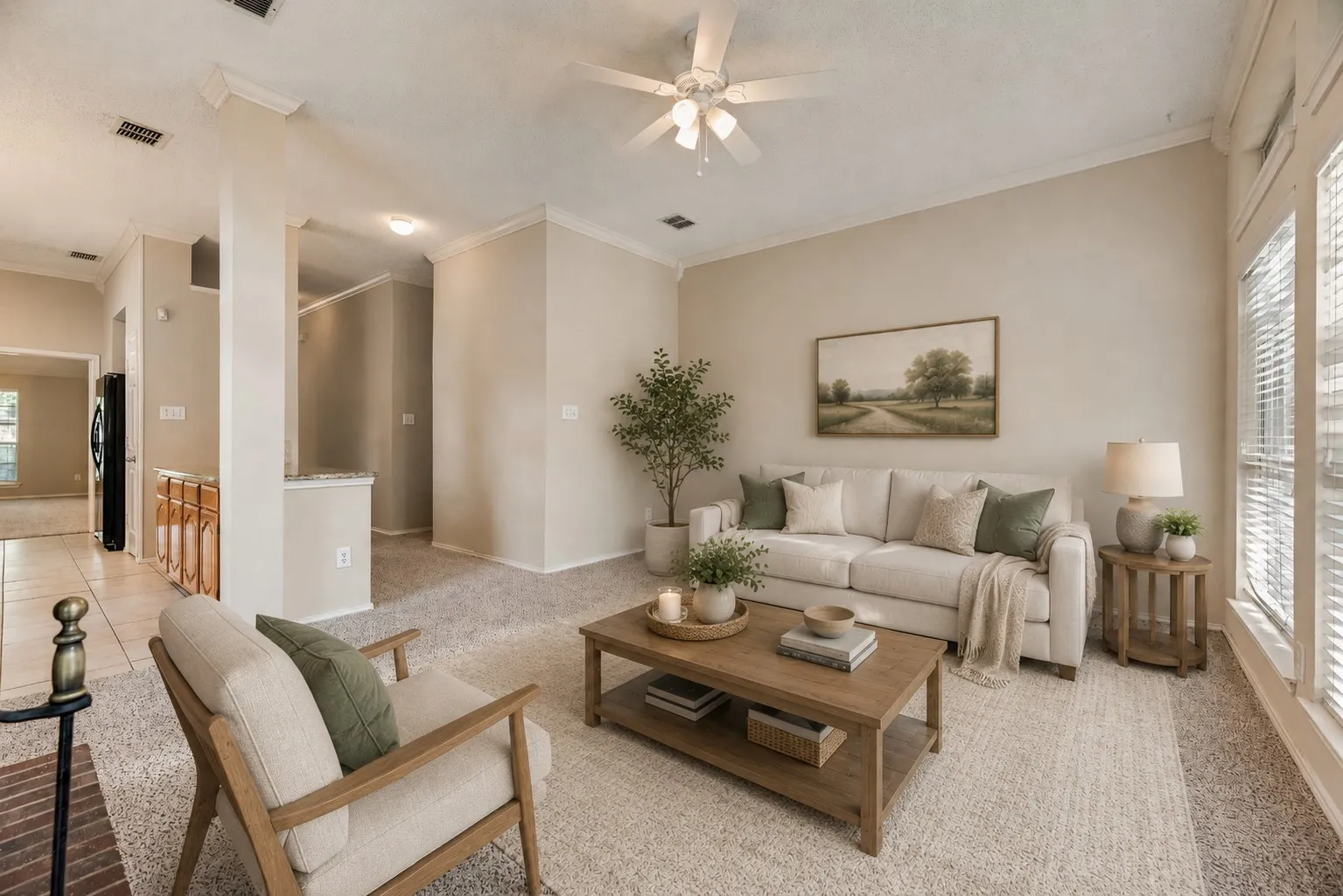 Spacious living area featuring neutral-toned carpeting, ample natural light from large windows, and a ceiling fan