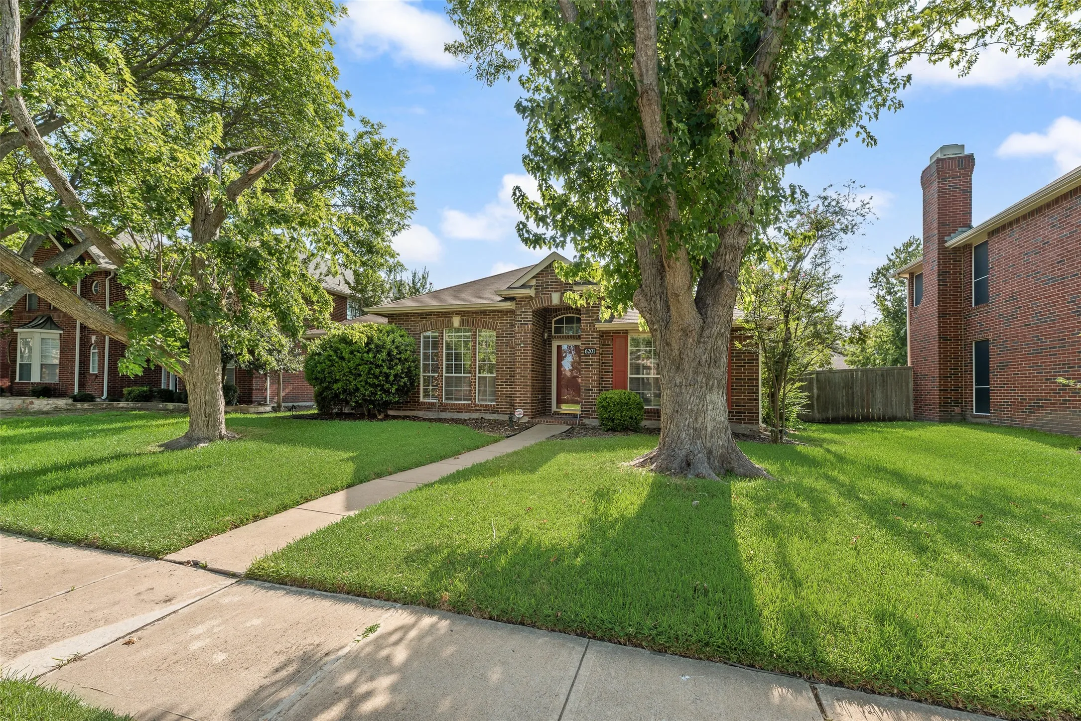 Brick exterior residence featuring a prominent chimney structure and mature trees