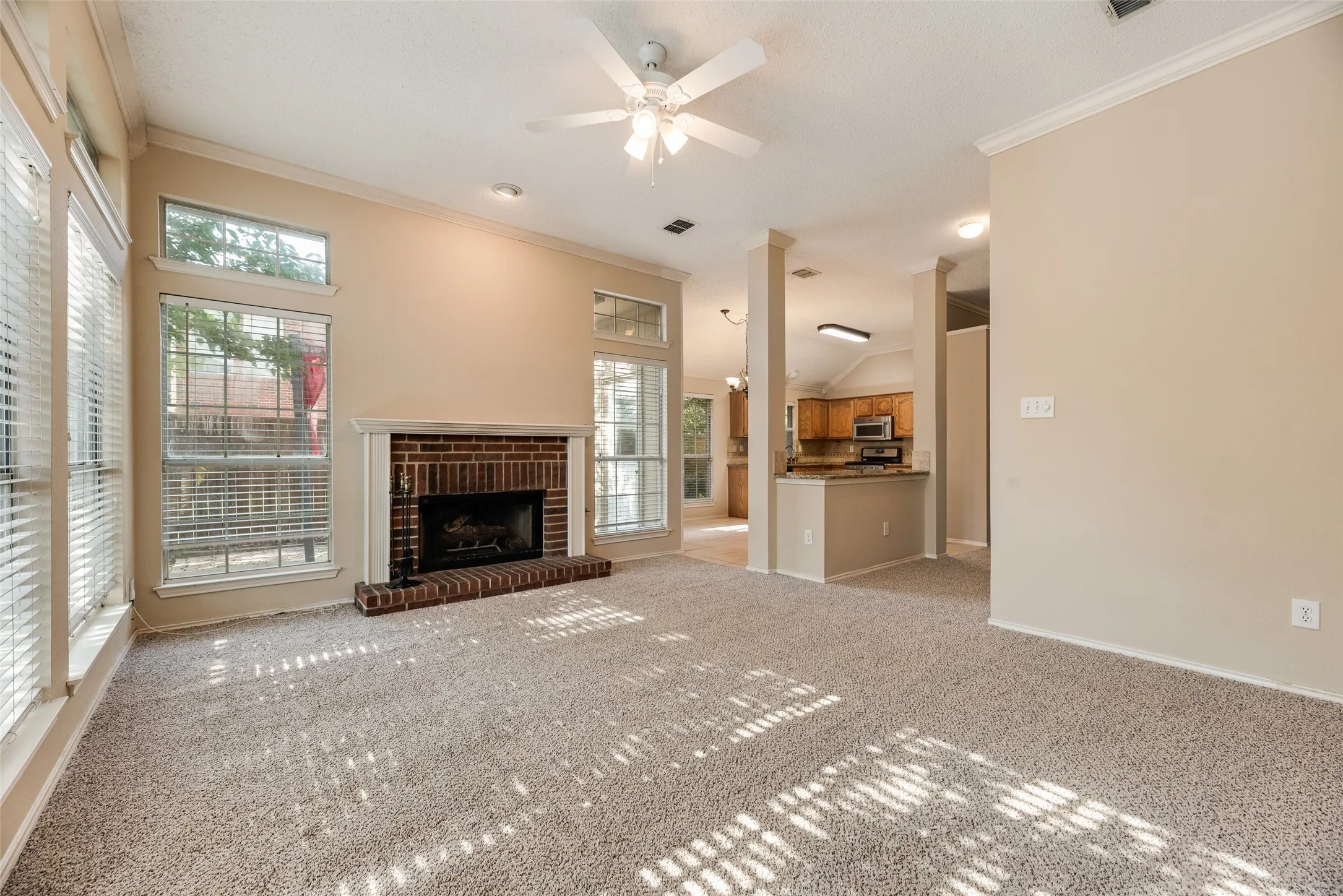 Living room featuring a brick fireplace with a white mantel, vaulted ceilings, and a ceiling fan