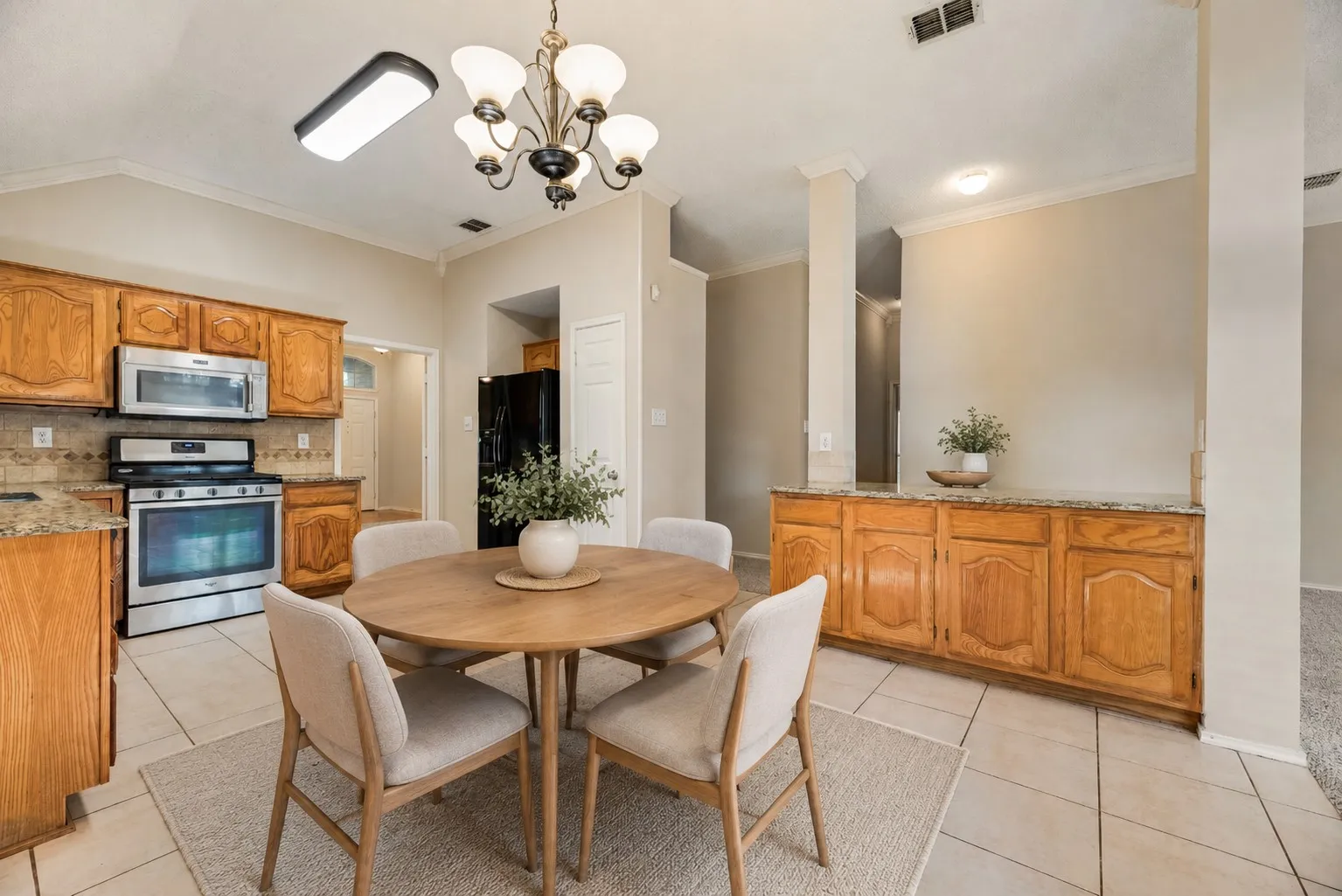 Kitchen and dining area featuring wood cabinetry, stainless steel appliances, granite countertops, and tile flooring