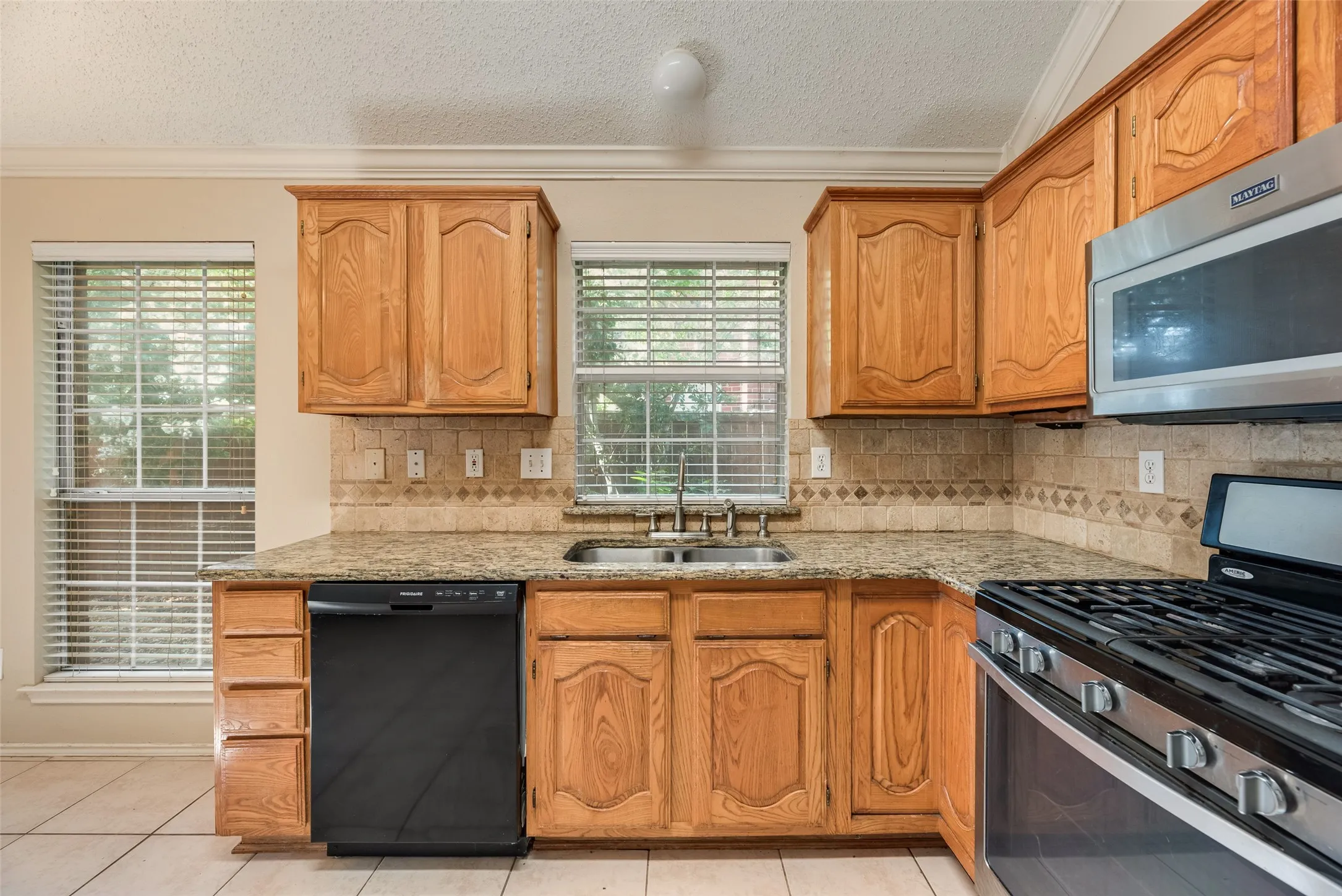 Kitchen featuring wood cabinetry, granite-finish countertops, and a tile backsplash