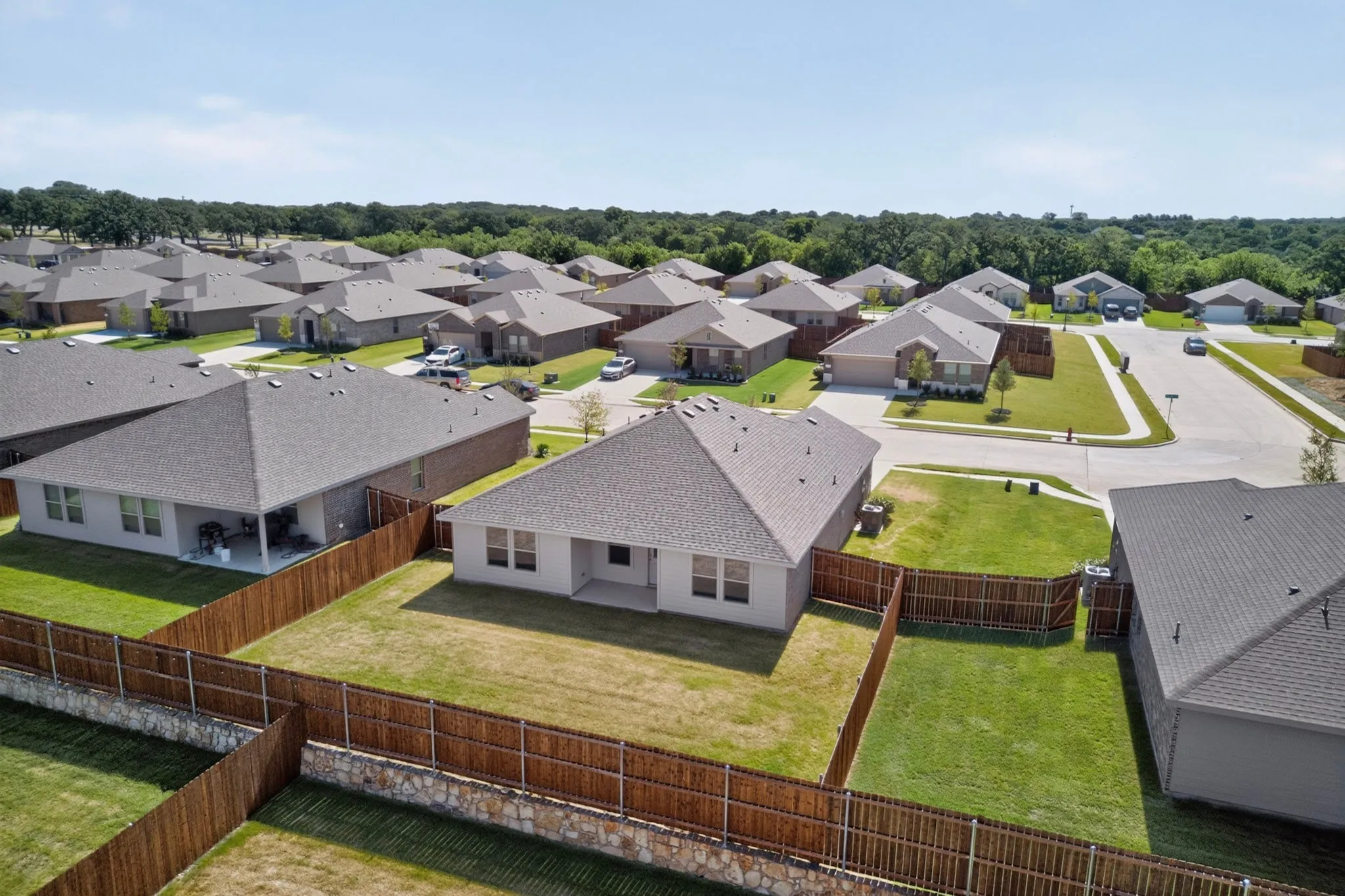 Aerial view showcasing a residential street with single-story homes featuring neutral-toned exteriors and dark shingle roofs