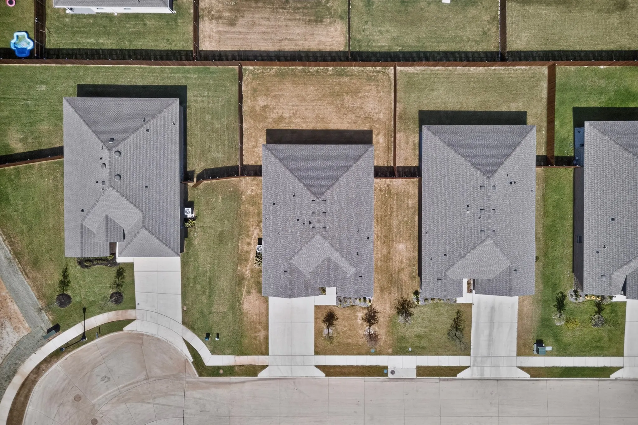 Aerial perspective showcasing multiple properties with uniform gray shingle roofing