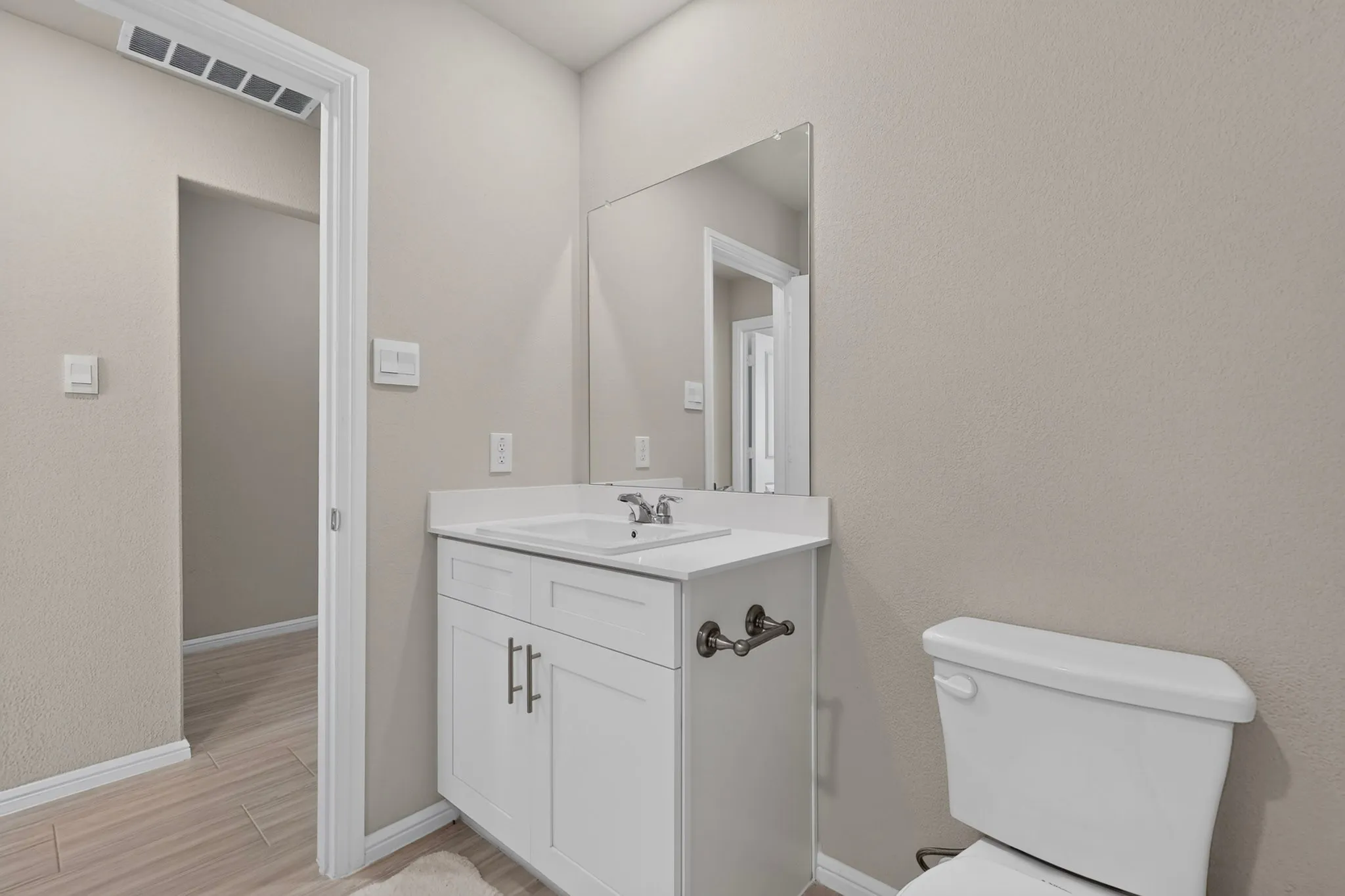 Bathroom vanity with white cabinetry, a single basin sink, and a rectangular mirror