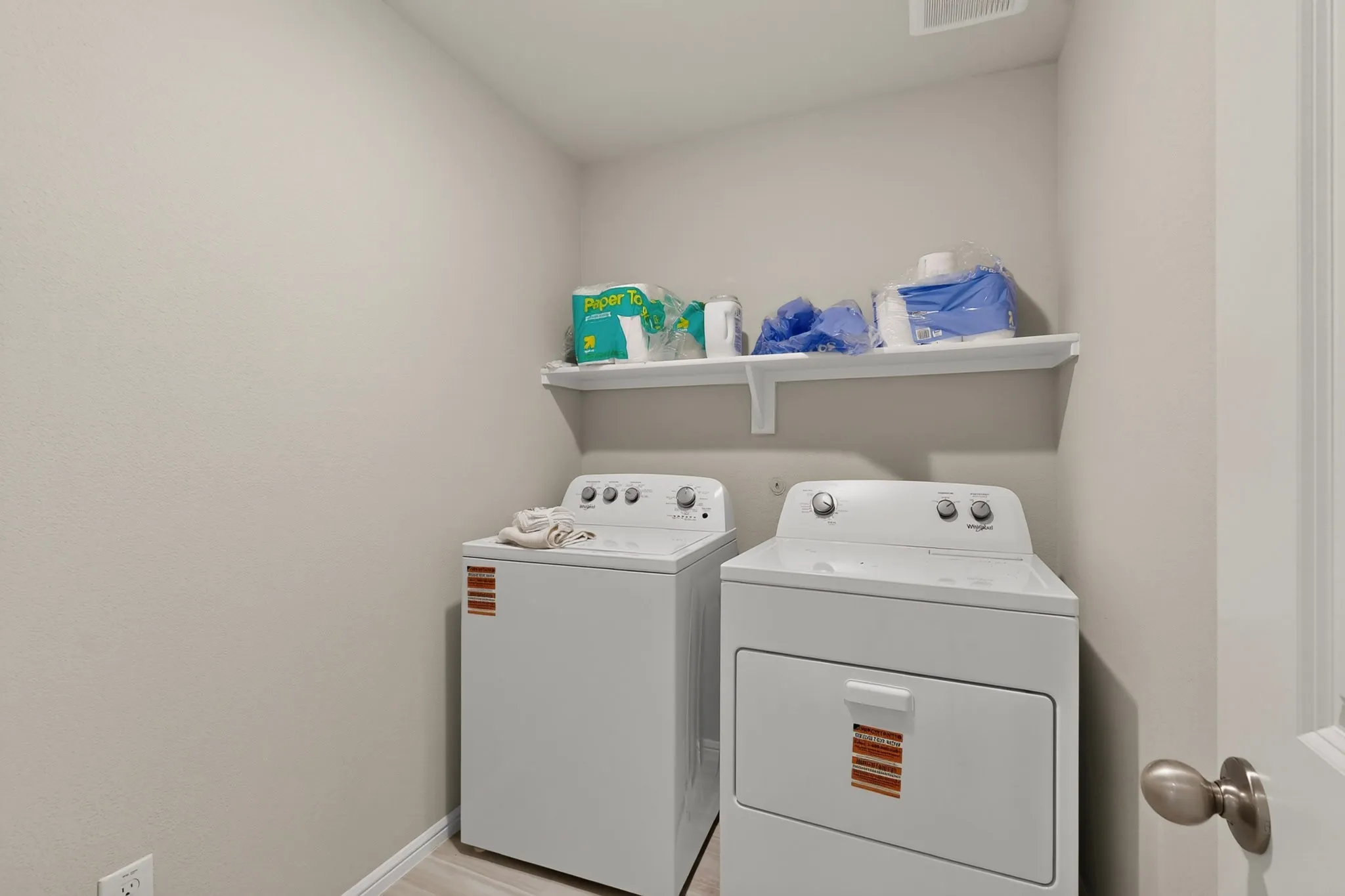 Dedicated laundry area featuring a white top-load washing machine, a white front-load dryer, and a built-in wall shelf for storage