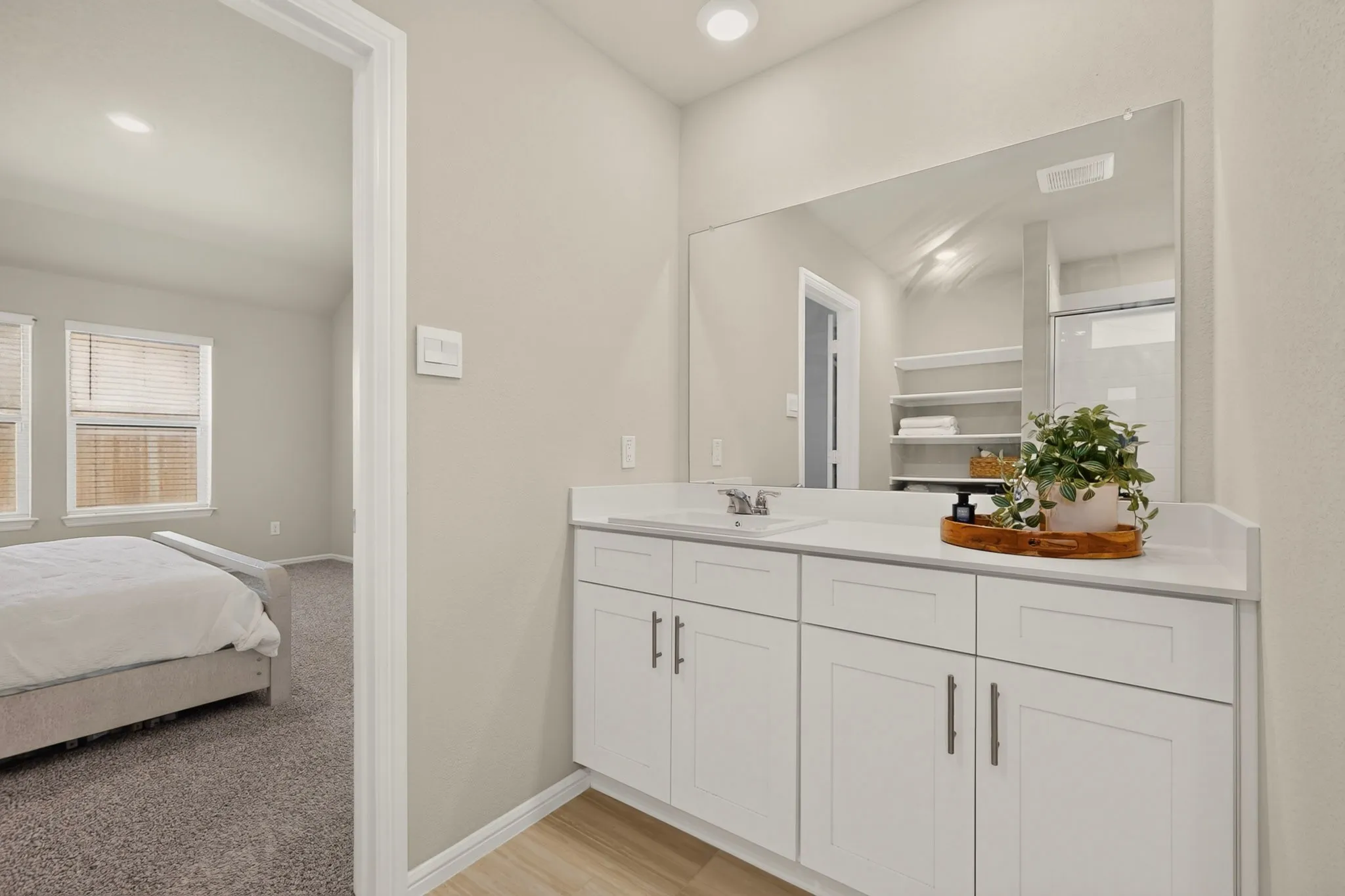 Bathroom vanity featuring a white countertop with integrated sink, white shaker-style cabinetry, and wood-finish flooring
