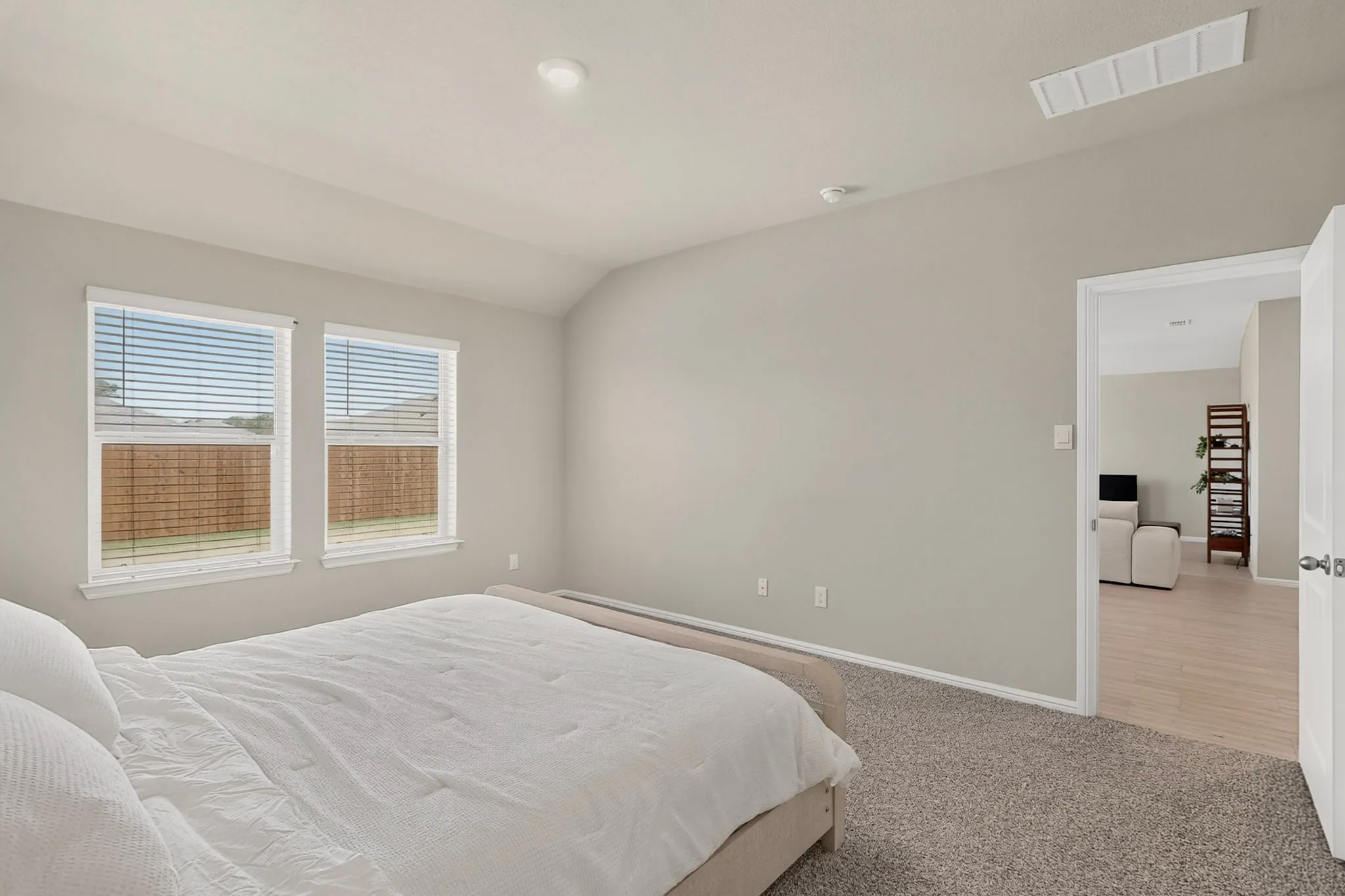 Bedroom featuring light neutral walls and a vaulted ceiling