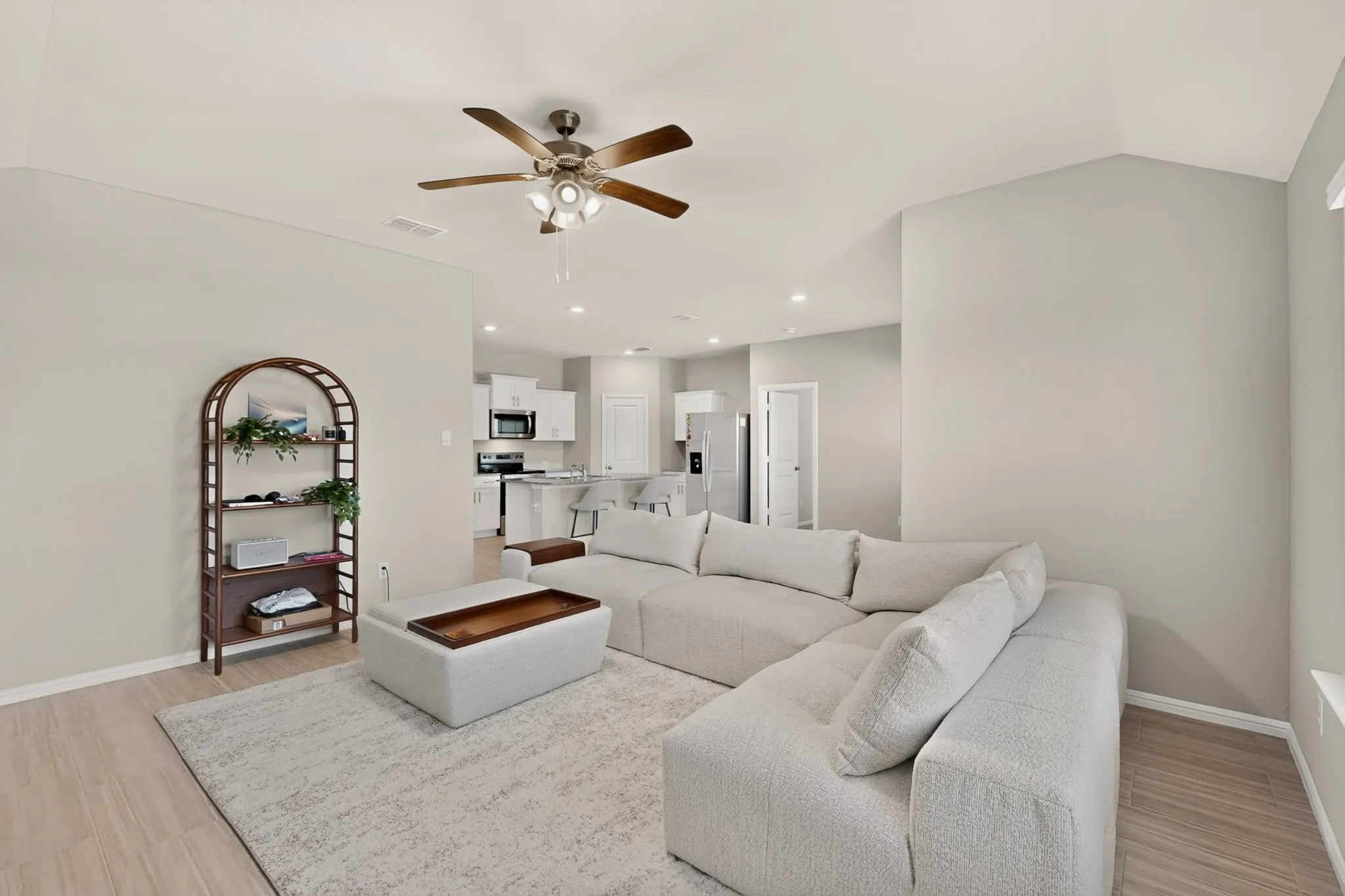 Open-concept living area with vaulted ceilings, wood-finish flooring, and recessed lighting