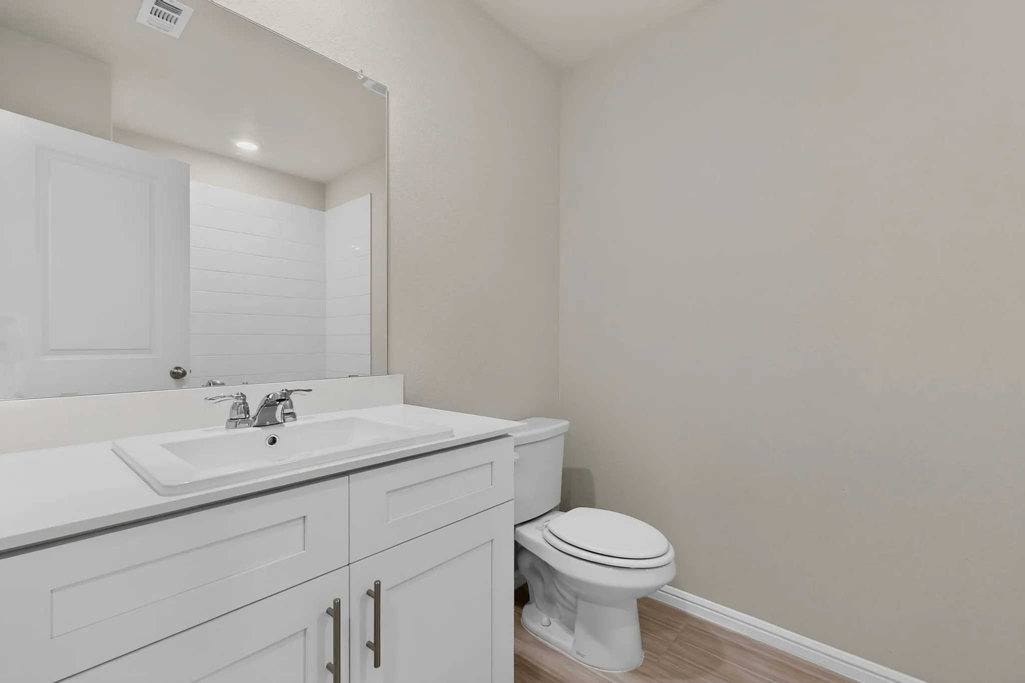 Bathroom featuring a white vanity with an integrated sink, polished chrome faucet, and a large mirror