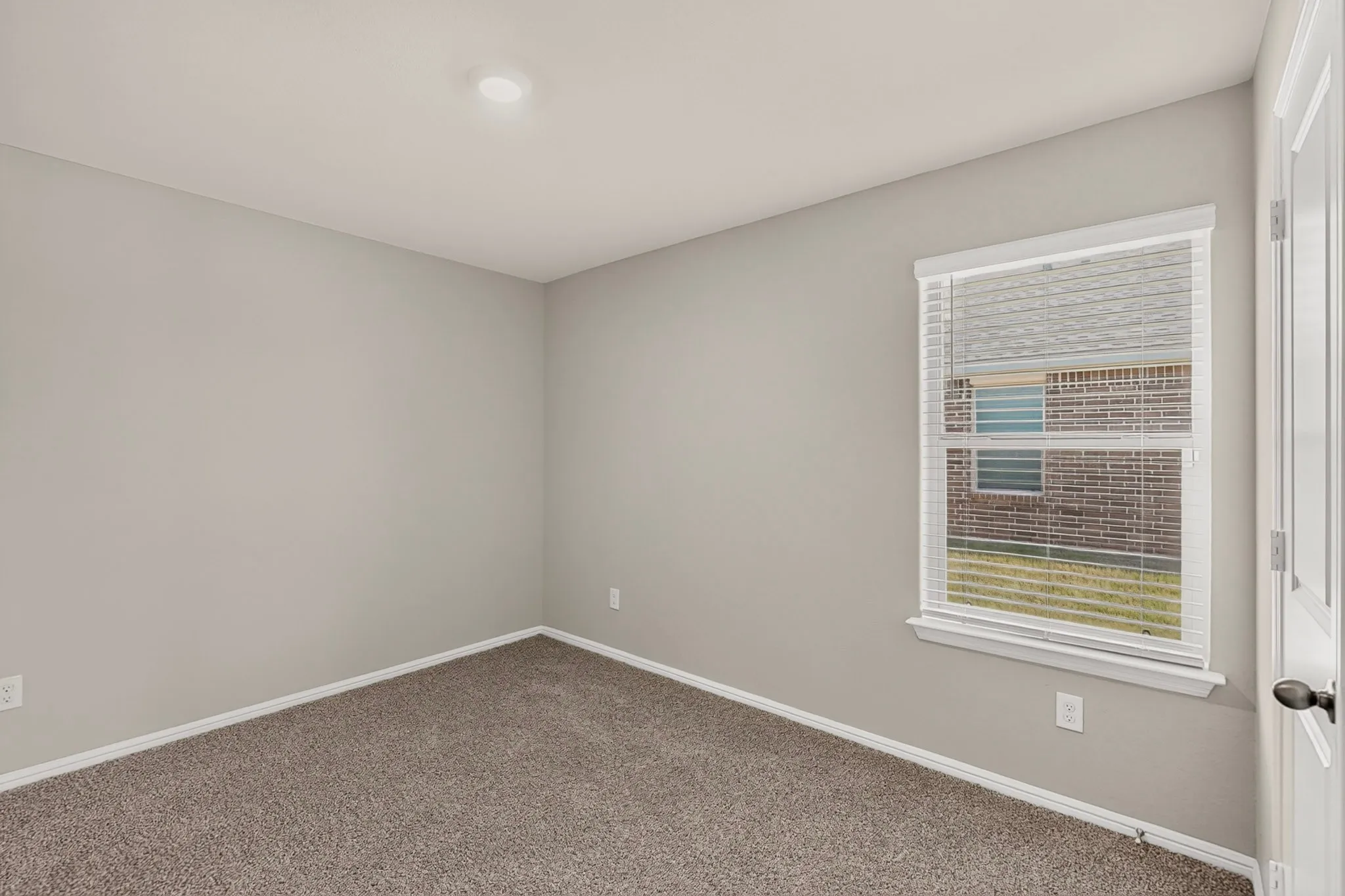 Carpeted interior space featuring light gray walls, white trim, a single window with blinds, and recessed lighting