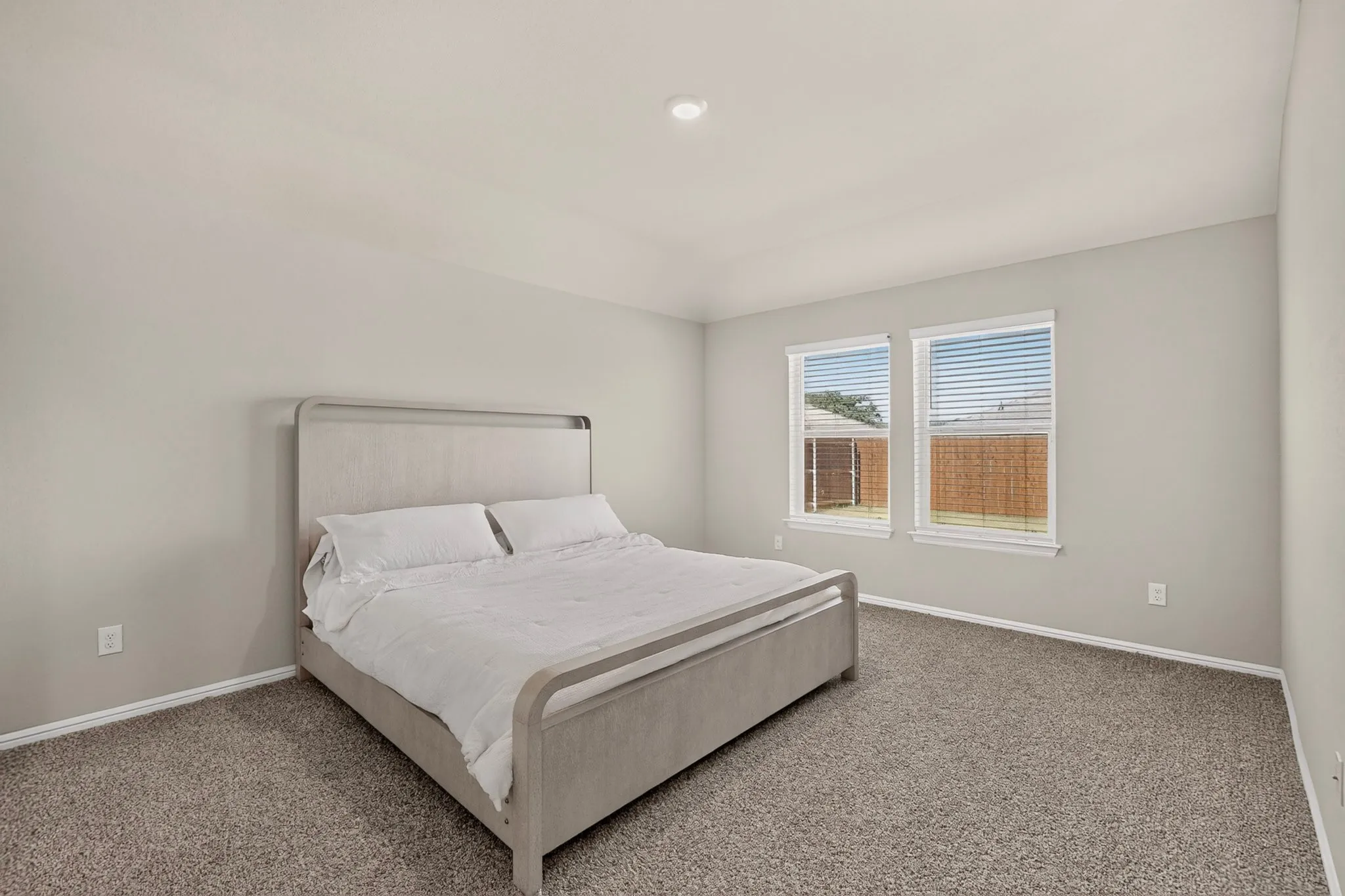Carpeted room featuring light gray walls, two windows with blinds, white trim, and a recessed ceiling light