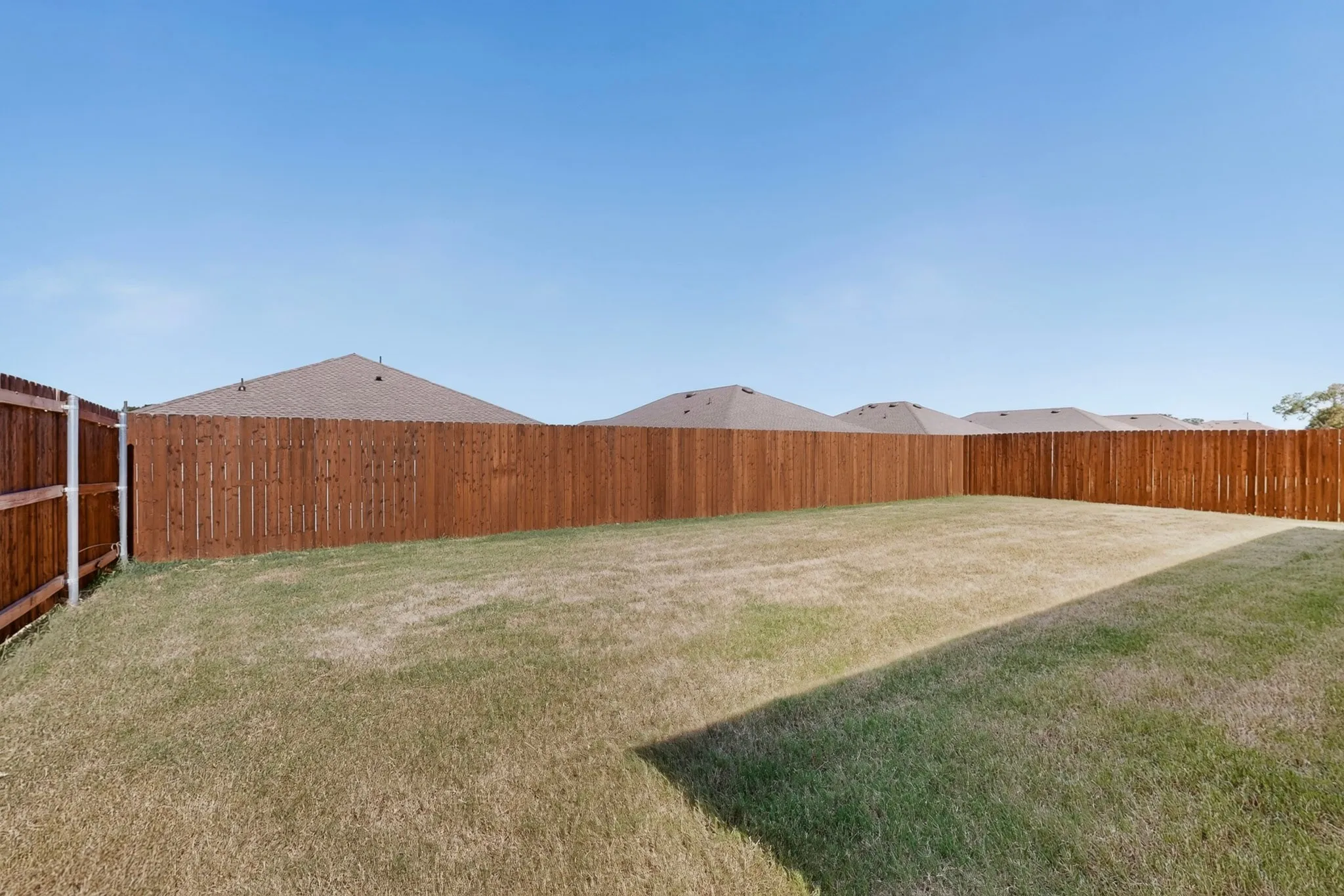 Spacious backyard featuring a wood privacy fence and a grass lawn