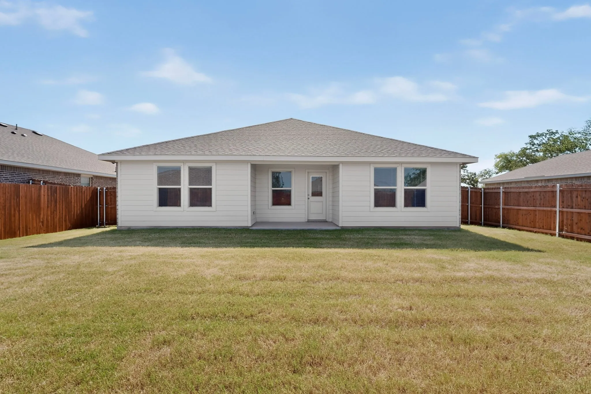 Expansive backyard featuring a large green space, privacy fencing, and a concrete patio