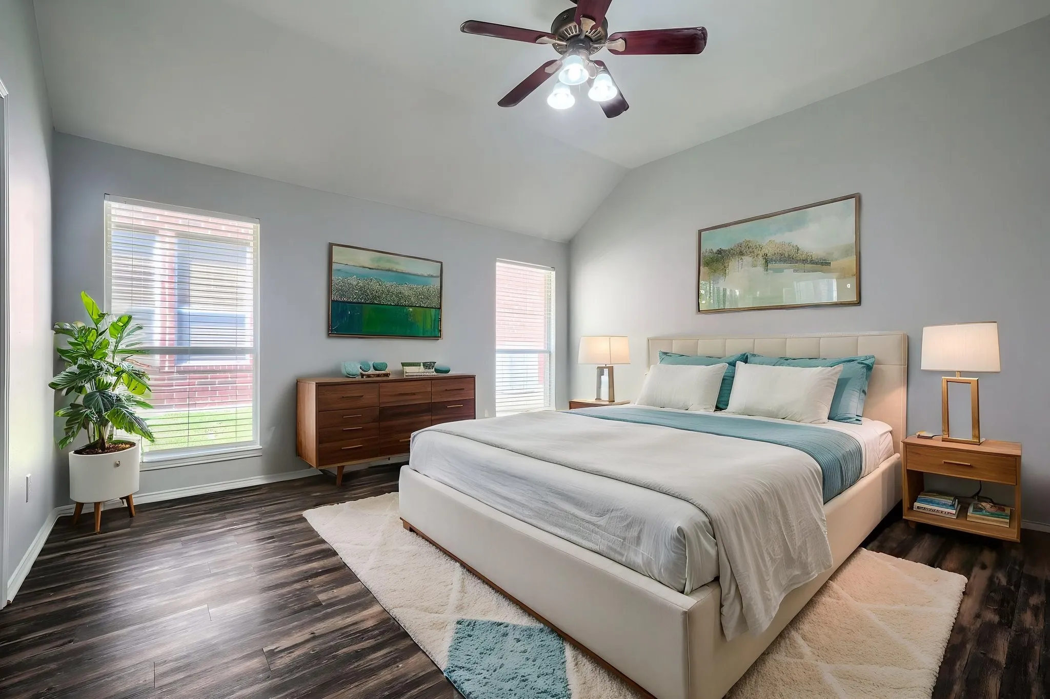 Spacious bedroom featuring vaulted ceilings, dark wood-finish flooring, and multiple windows with horizontal blinds