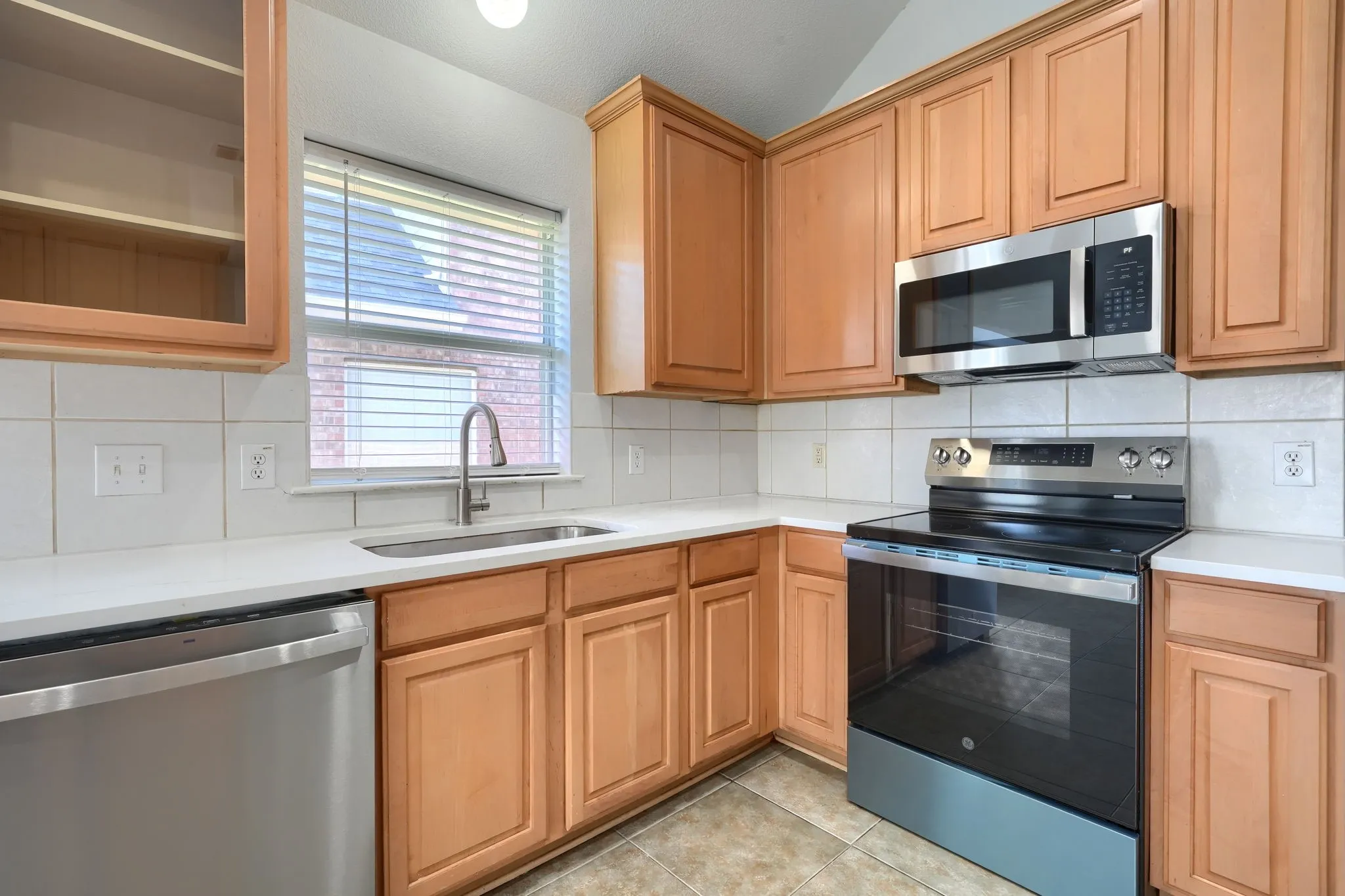 Kitchen featuring wood-finish cabinetry, stainless steel appliances, white countertops, and a white tiled backsplash