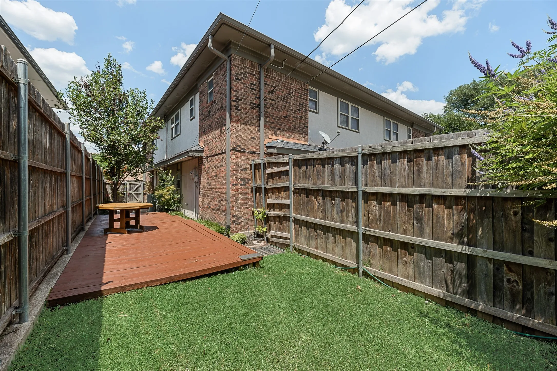 Private backyard featuring a wood deck, manicured lawn, and surrounding privacy fencing