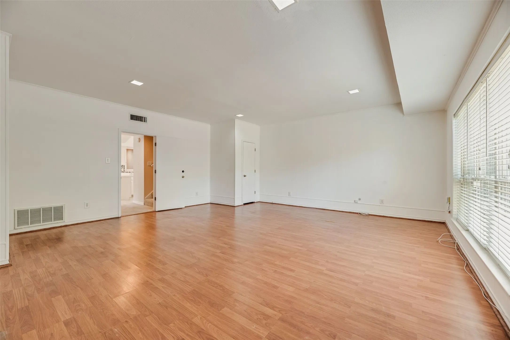 Expansive living room featuring wood-finish flooring, white walls, and recessed lighting