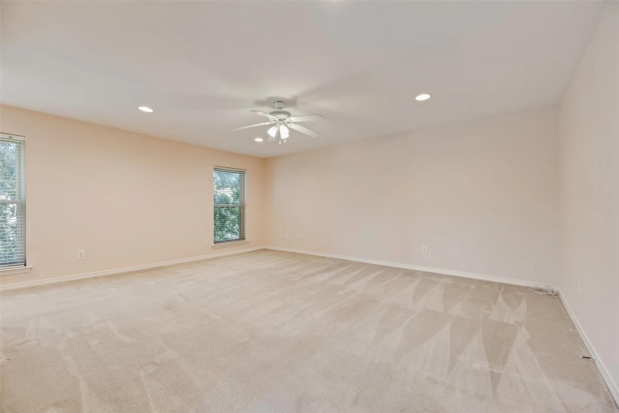 Spacious primary room featuring neutral carpeting, light-toned walls, and multiple windows