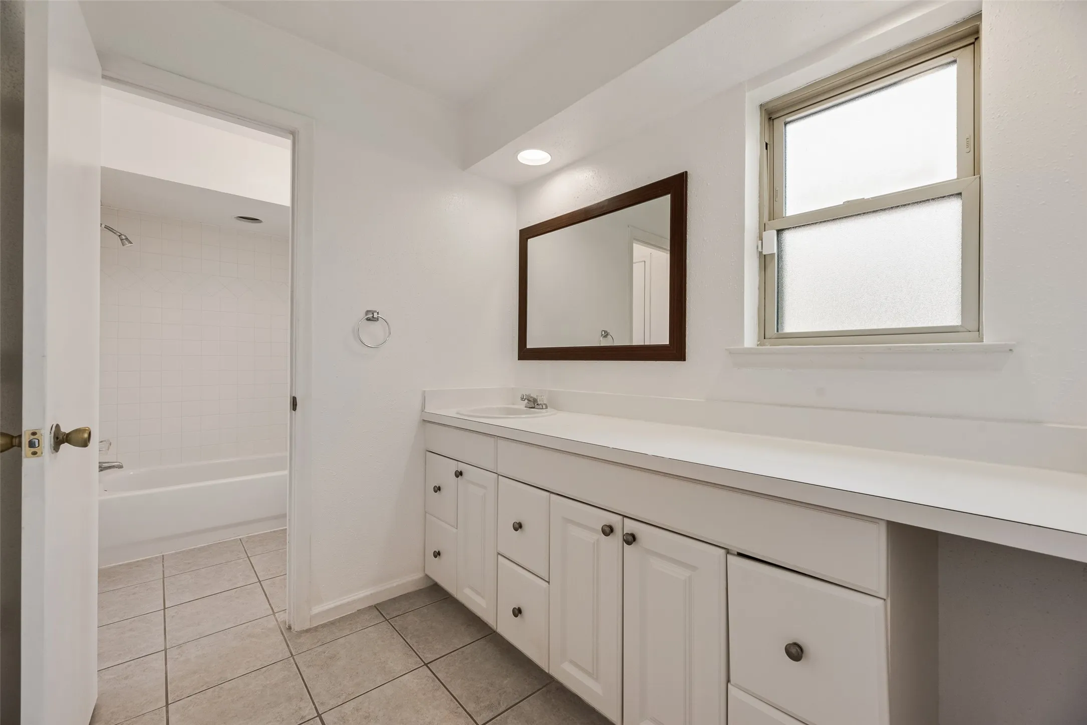 Bathroom featuring a white vanity with integrated sink, coordinating countertop, and a framed mirror