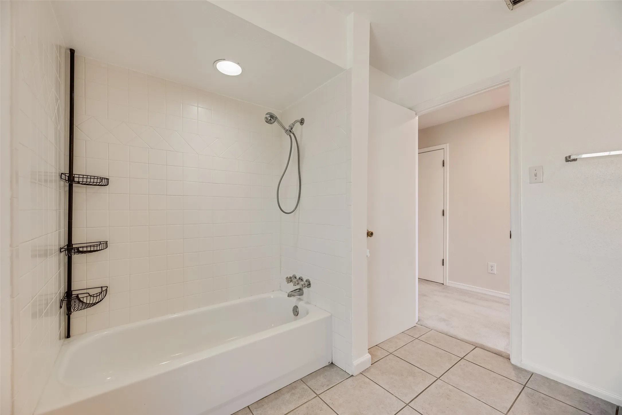 Bathroom featuring a white bathtub, ceramic tile surround, recessed lighting, and tile flooring