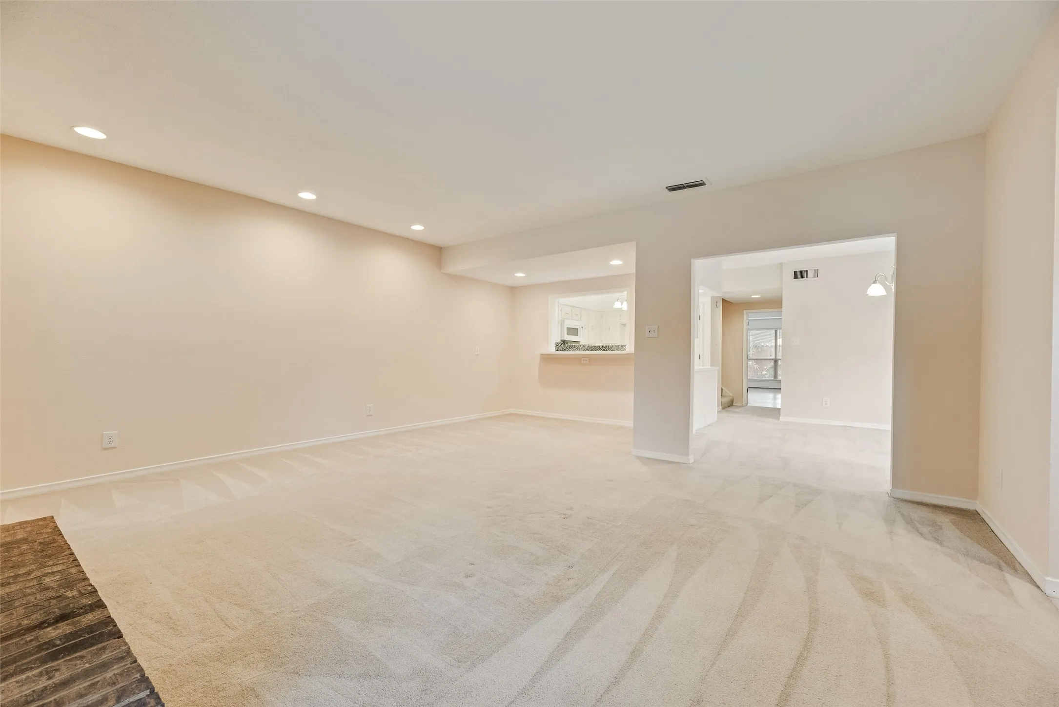 Spacious room featuring a brick fireplace, neutral carpet, and recessed lighting
