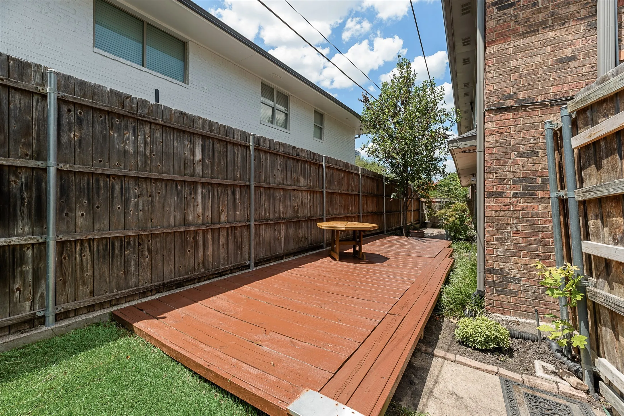 Private backyard featuring a wood deck, manicured lawn, and surrounding privacy fencing