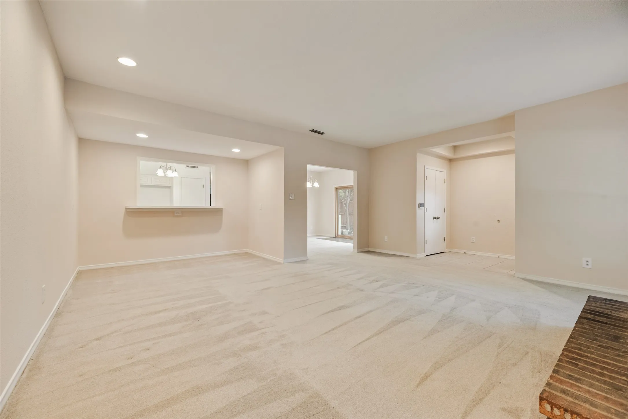 Spacious room featuring a brick fireplace, neutral carpet, and recessed lighting