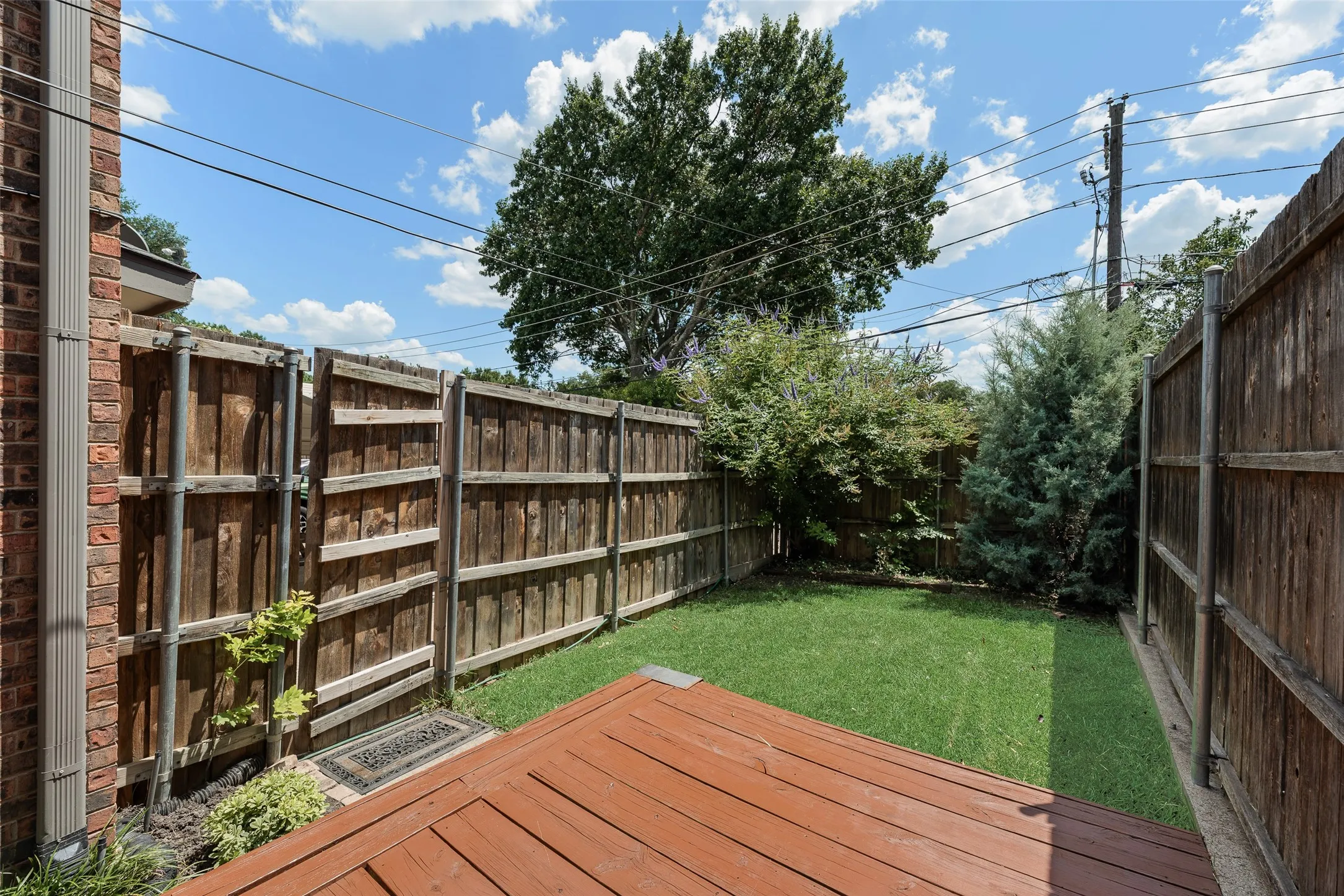 Private backyard featuring a wood deck, manicured lawn, and surrounding privacy fencing