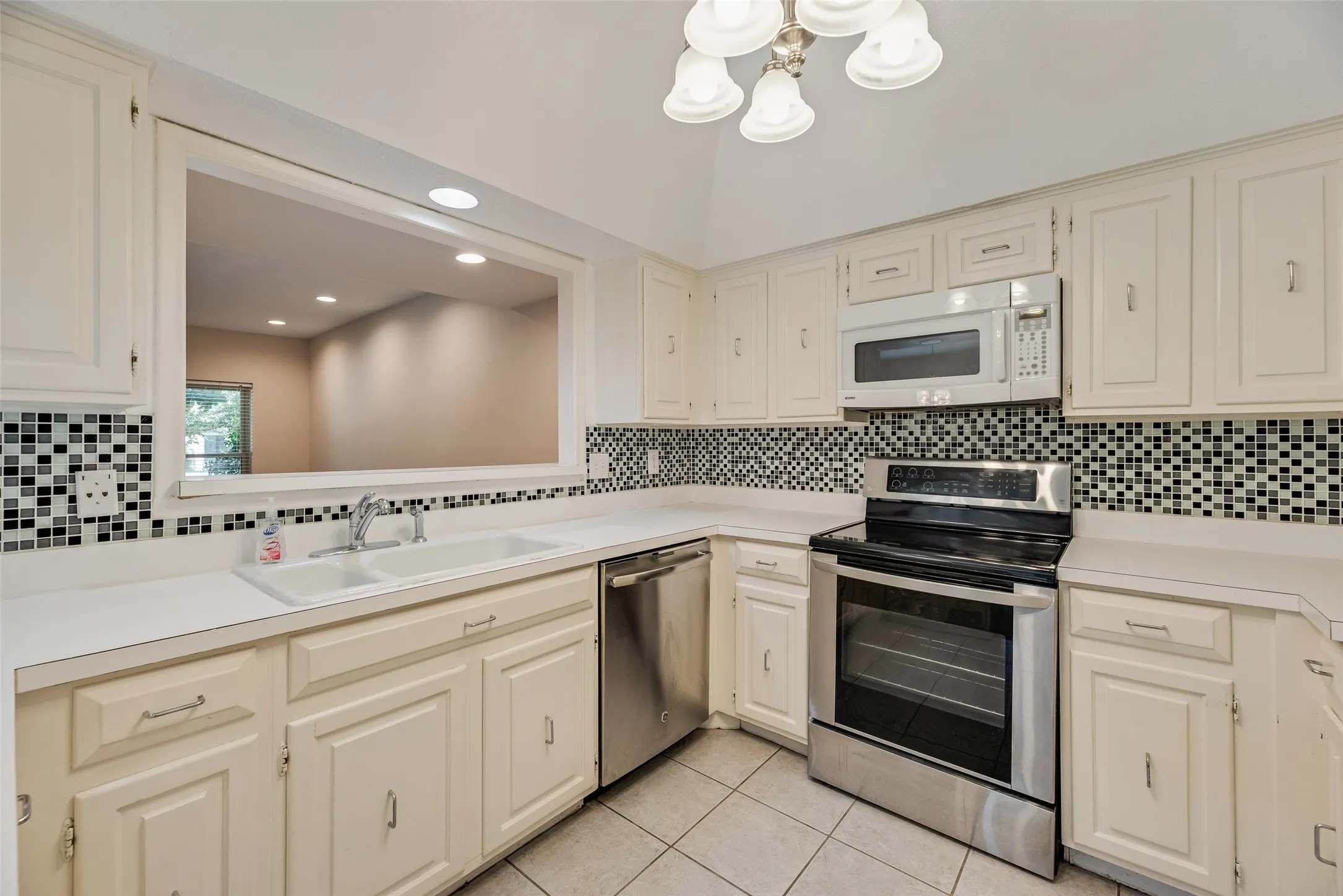Kitchen featuring white cabinetry, a black and white mosaic tile backsplash, and white countertops