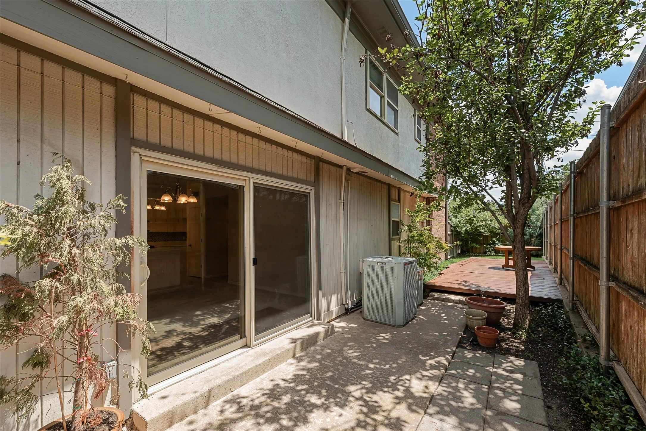 Private paved patio area featuring a wooden privacy fence, and sliding glass door access