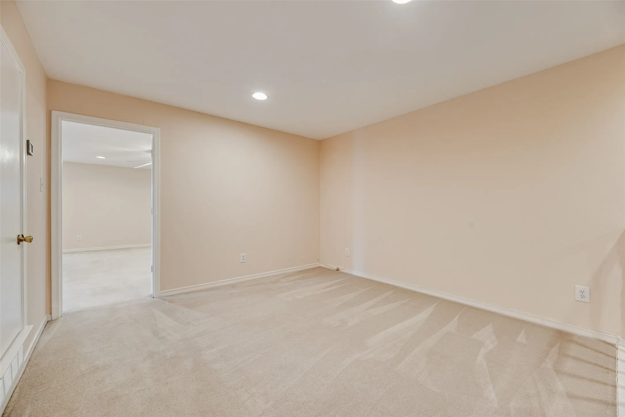Neutral-toned carpeting and walls create a versatile interior space with recessed lighting