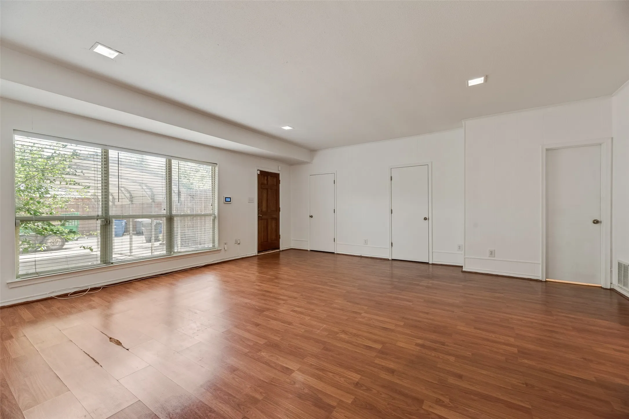 Expansive living room featuring wood-finish flooring, white walls, and recessed lighting