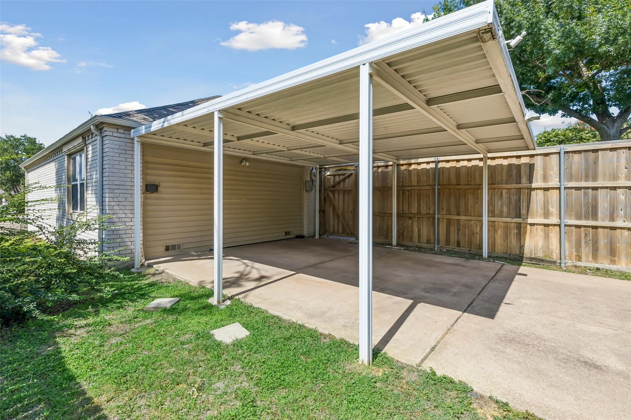 This shade structure doubles as a covered patio for outdoor entertaining. It would be great to open the fence with a wide, double gate to connect the backyard!