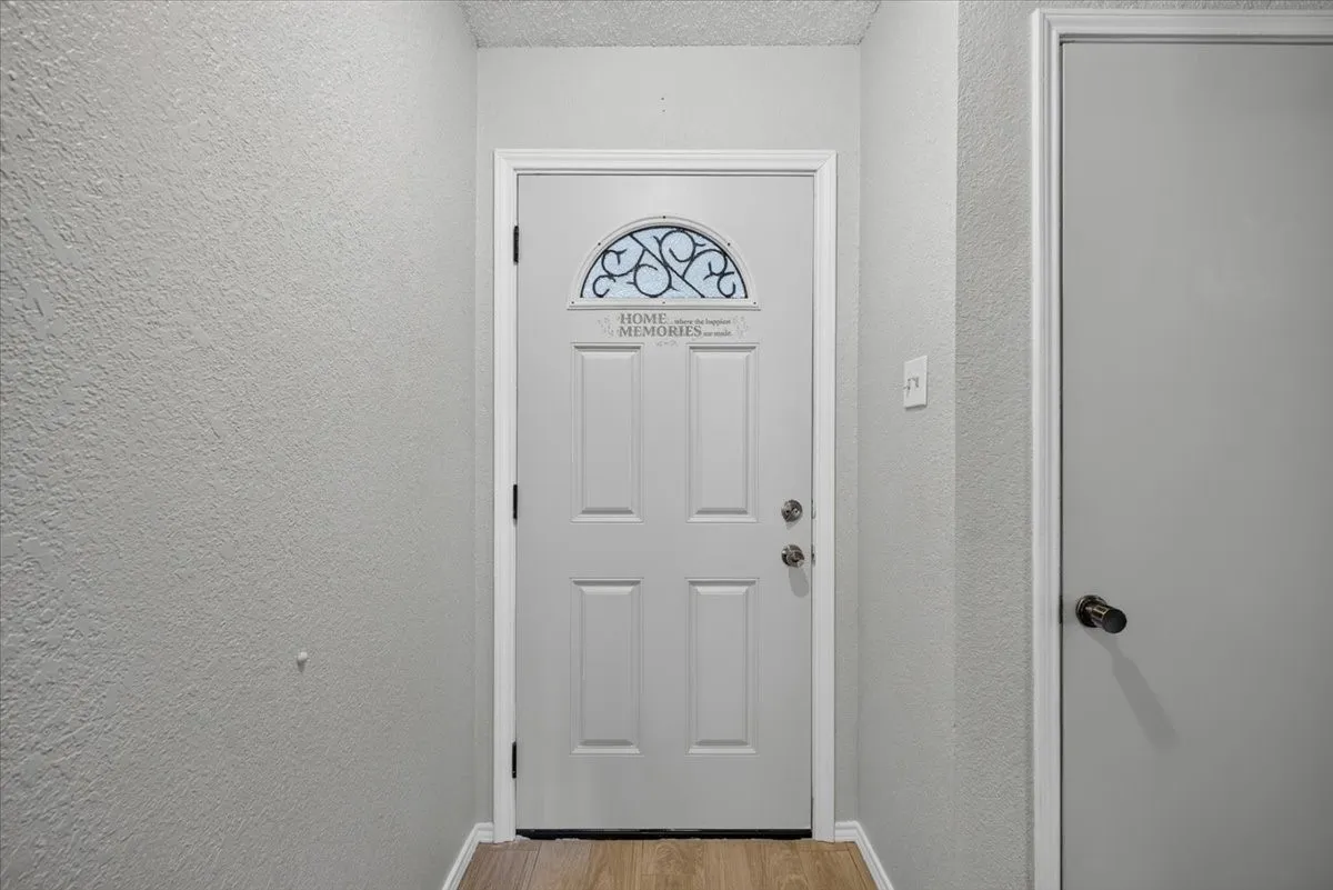 Entryway featuring a paneled door with an arched decorative glass insert and light wood-finish flooring