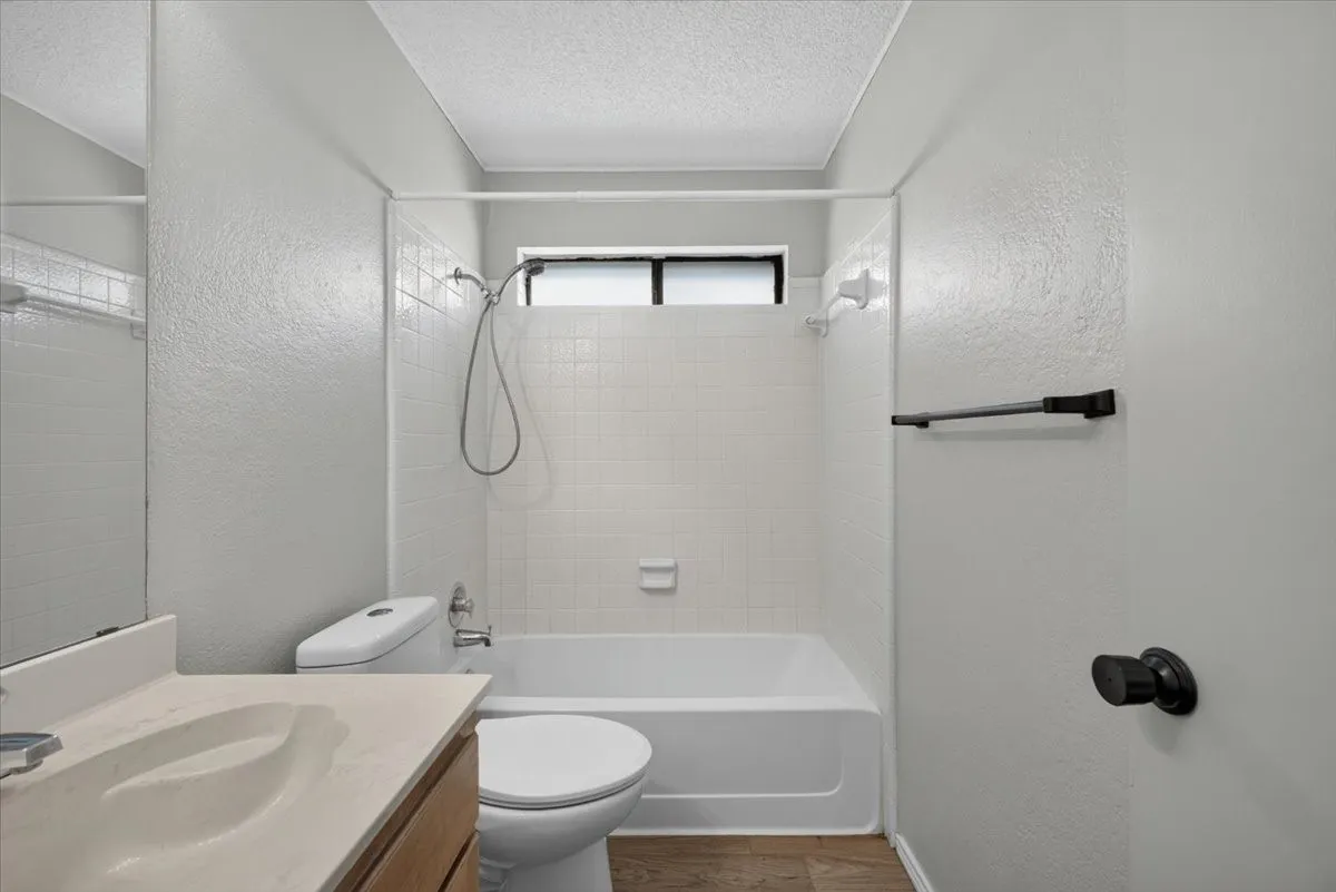 Bathroom featuring a white bathtub with subway tile surround, single window, and a built-in vanity with an integrated sink