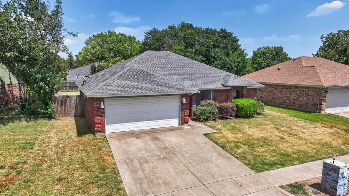 Brick facade home featuring an attached two-car garage, concrete driveway, and mature landscaping