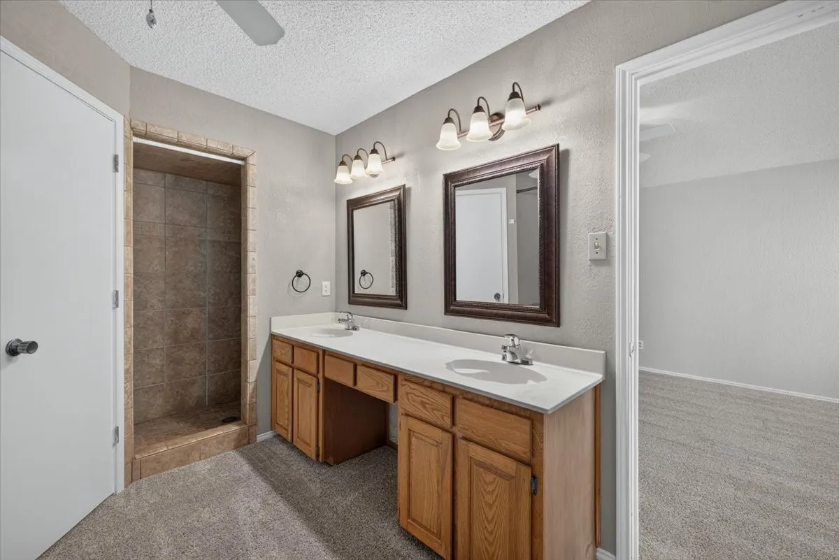Bathroom featuring a dual vanity with light countertops, wood cabinetry, and framed mirrors