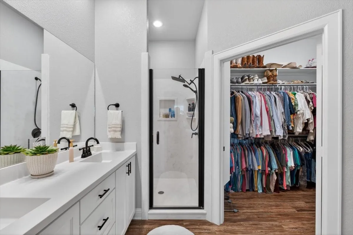 Bathroom featuring a double vanity with white countertops, matte black fixtures, and a glass-enclosed shower