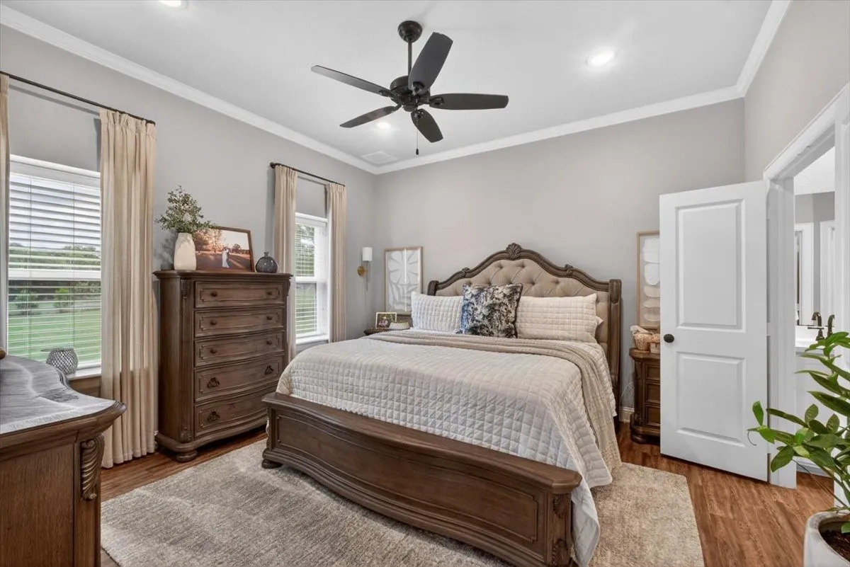 Spacious room featuring wood-finish flooring, two large windows, a ceiling fan, crown molding, and recessed lighting