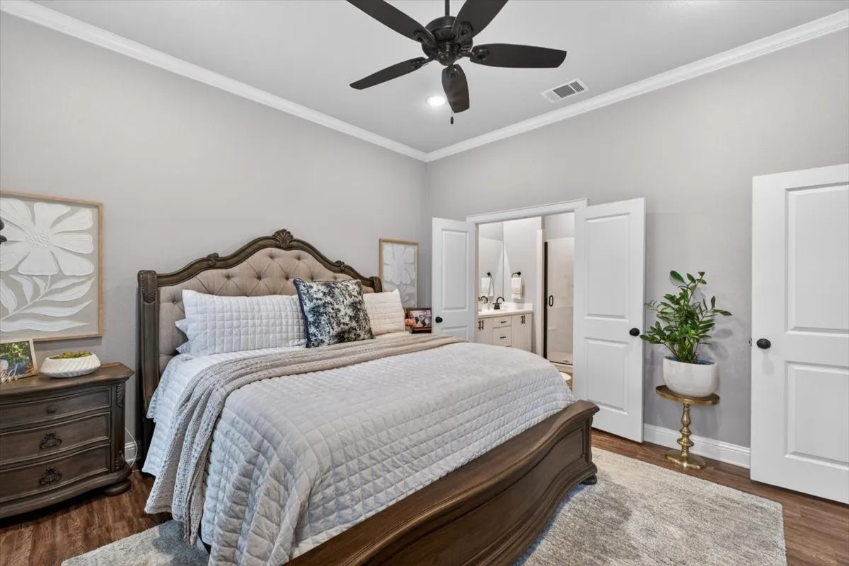 Bedroom featuring wood-finish flooring, crown molding, and a ceiling fan
