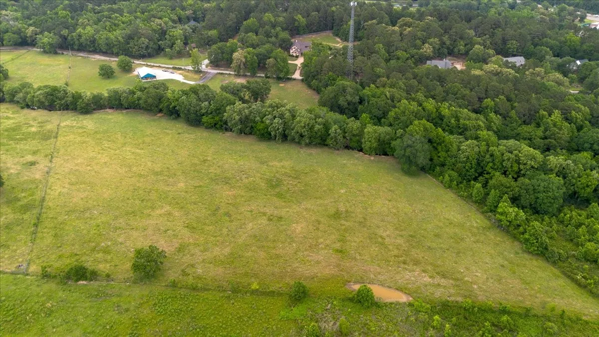 Expansive land parcel featuring open pastures, wooded areas, and a natural pond