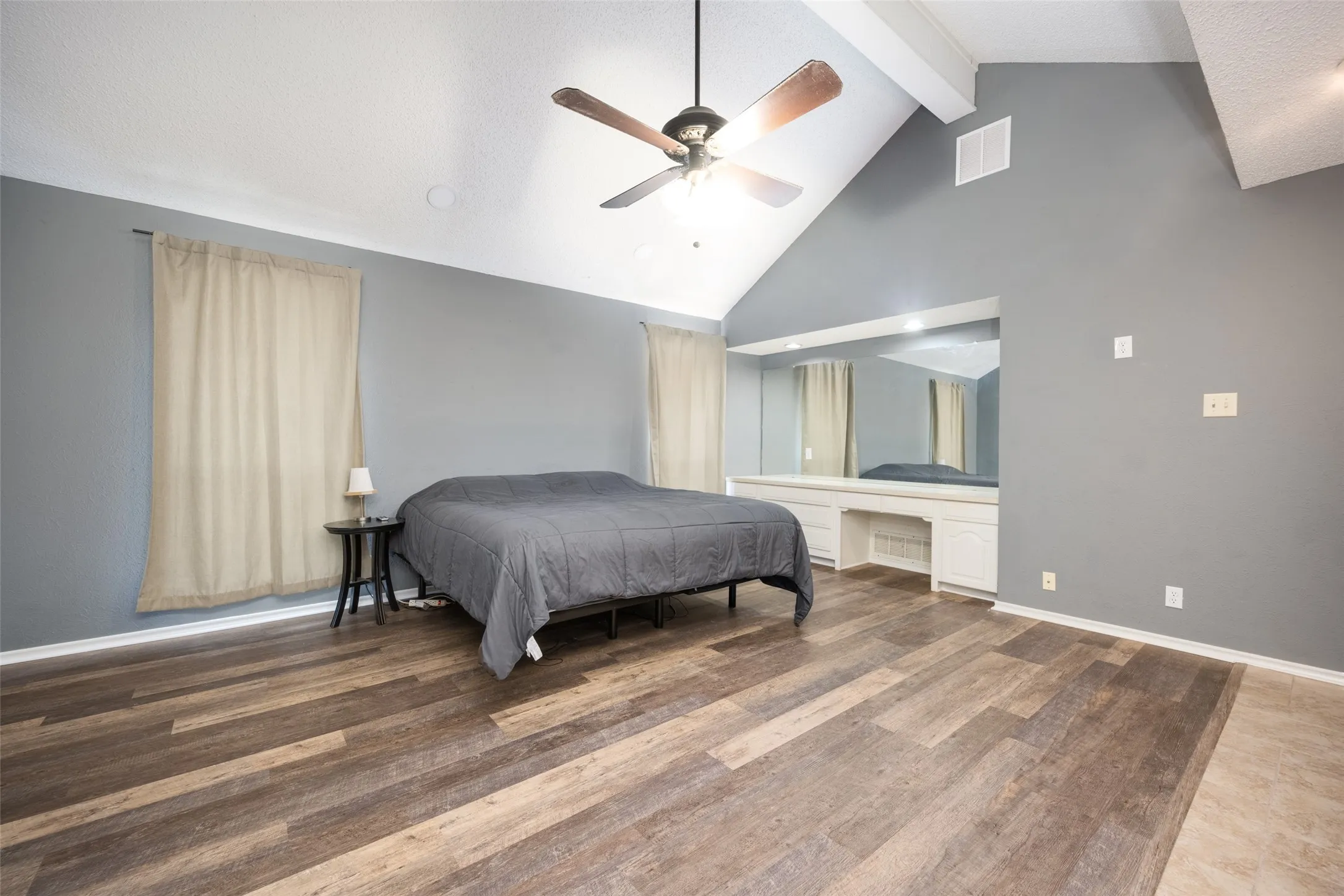 Vaulted ceilings with exposed beams and a ceiling fan, featuring wood-finish  luxury vinyl plank flooring