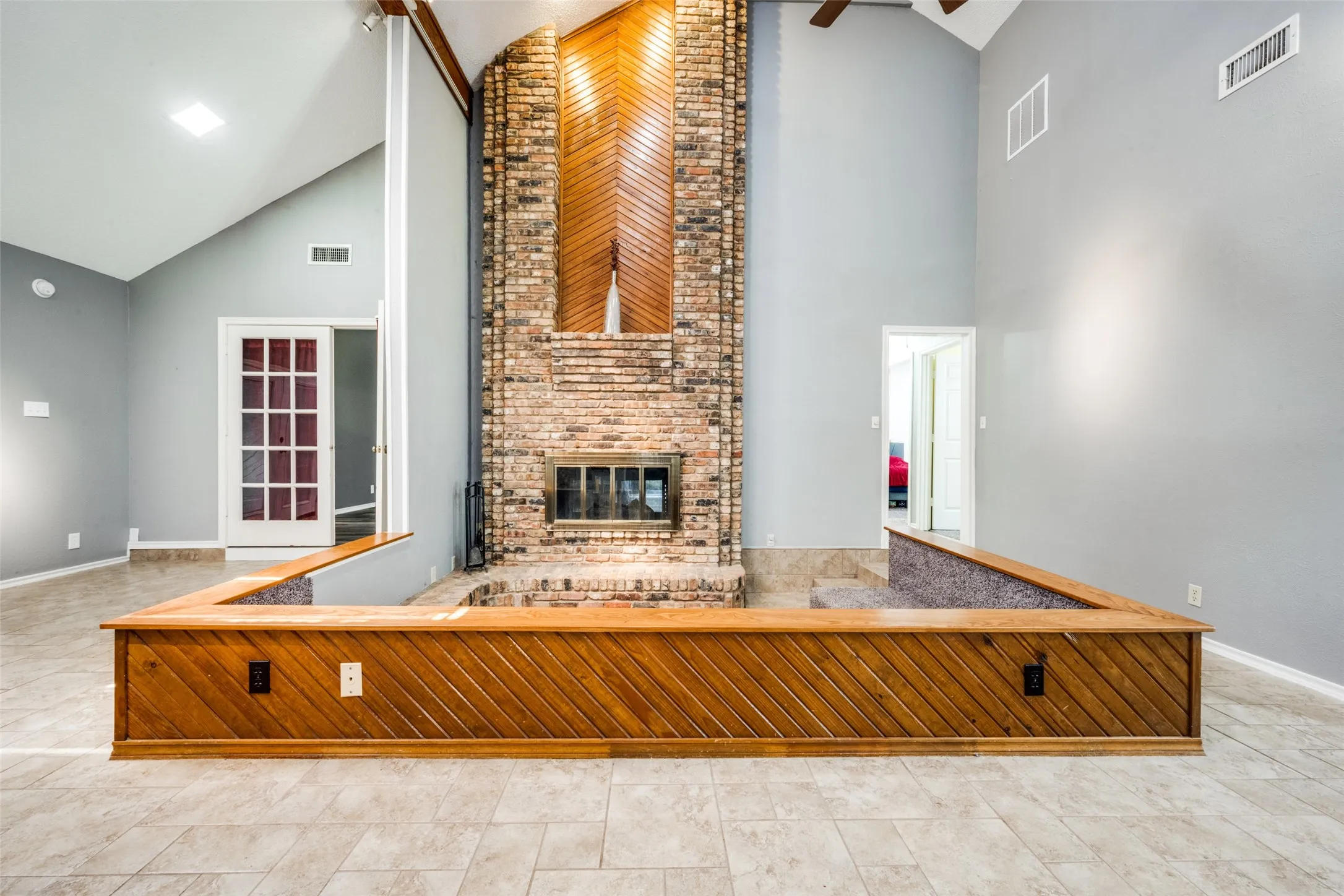 Vaulted ceilings complement a floor-to-ceiling brick fireplace with a wood-finish accent