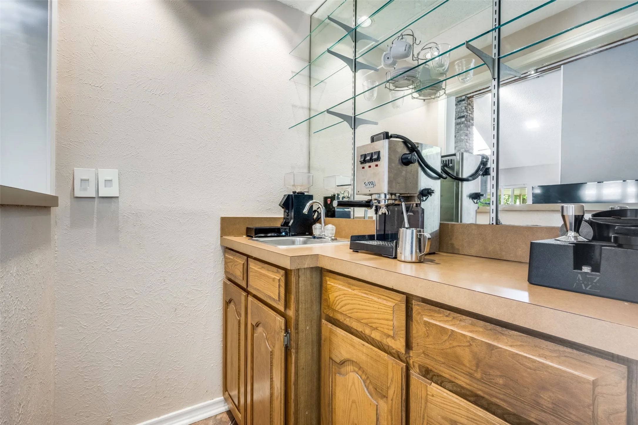 Built-in wet bar with a single basin sink, light-toned countertop, and wood cabinetry